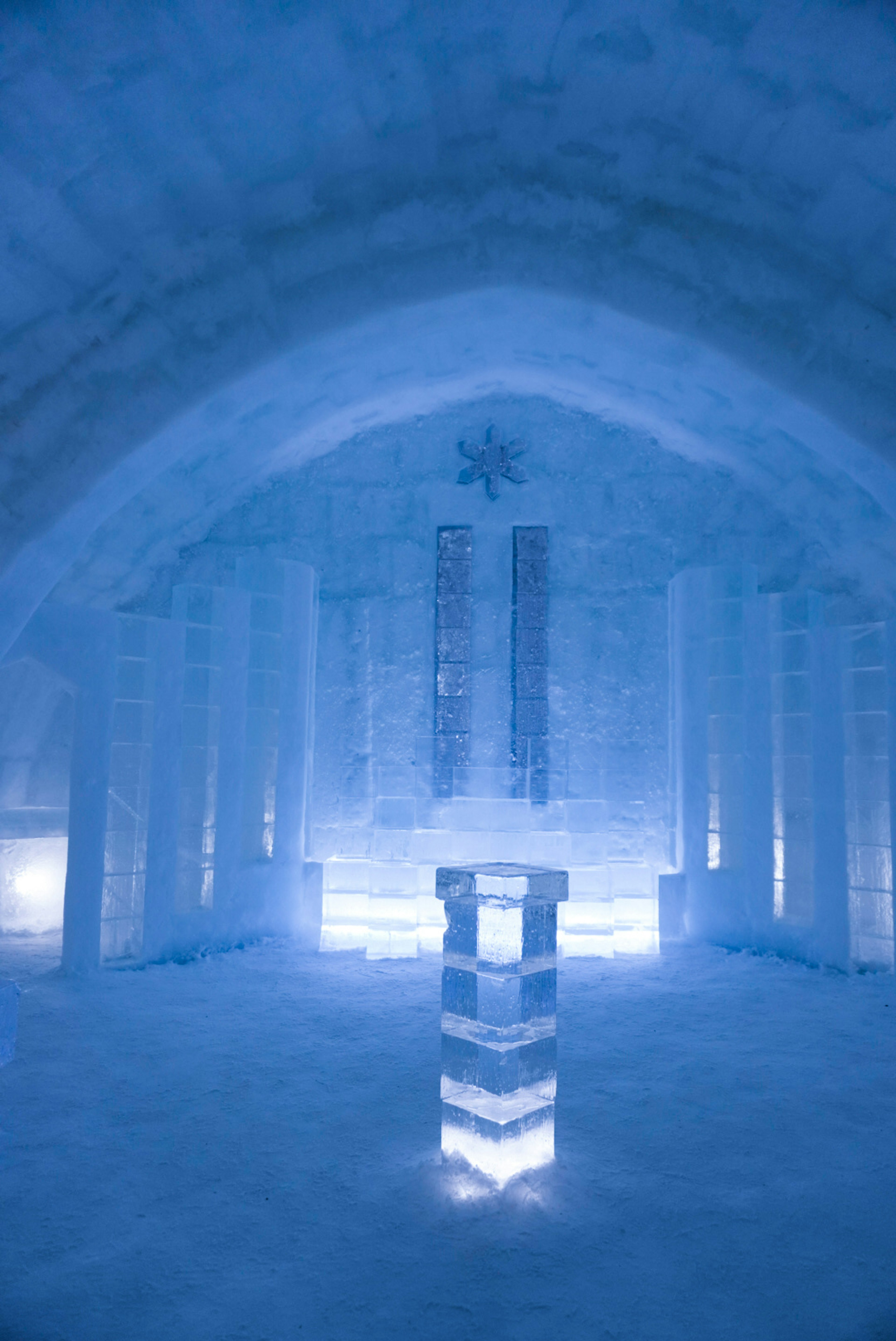 Pilastro illuminato in una stanza di ghiaccio blu decorata con sculture di ghiaccio