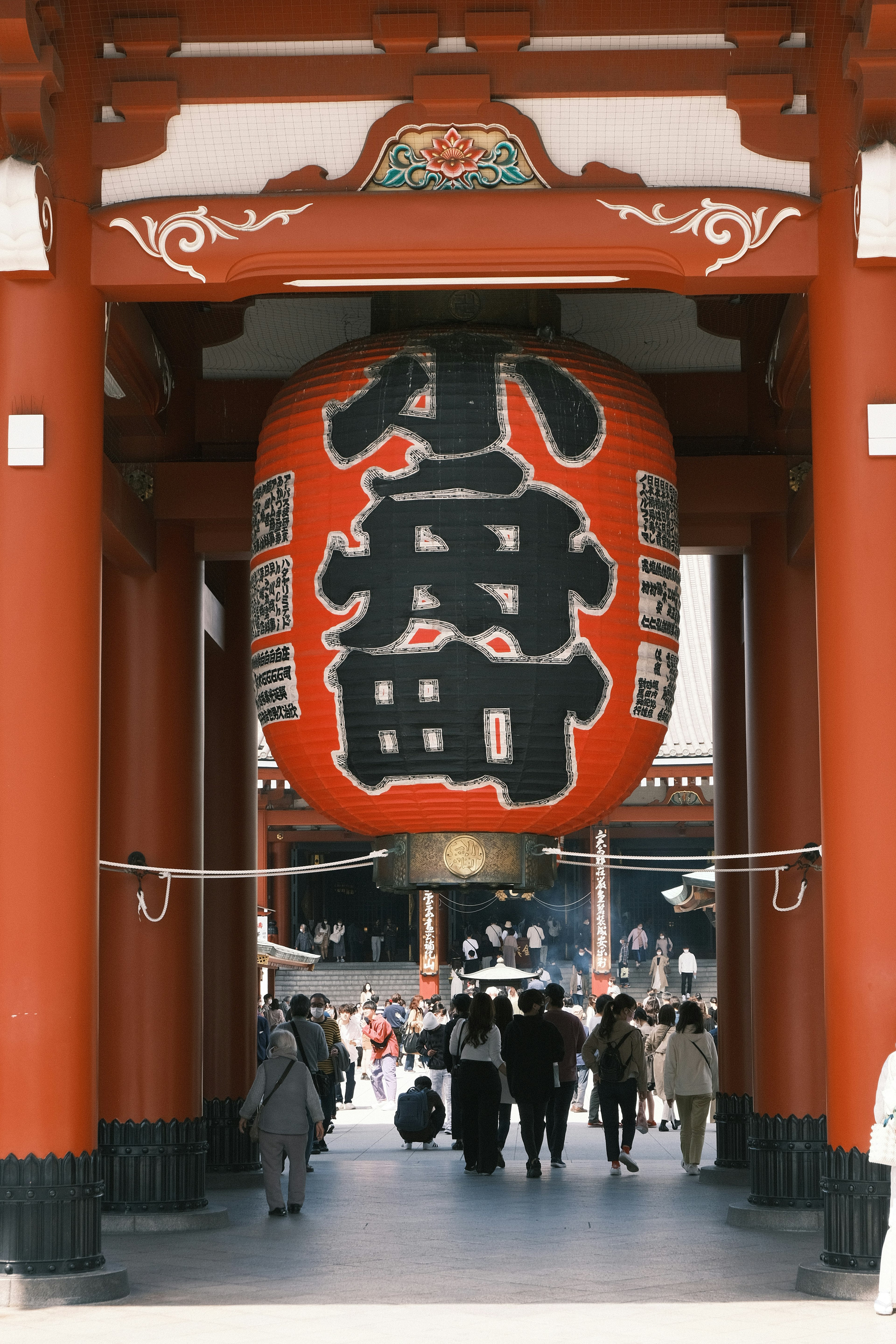 Personas caminando a través de una puerta roja con una gran linterna en la entrada del templo Senso-ji