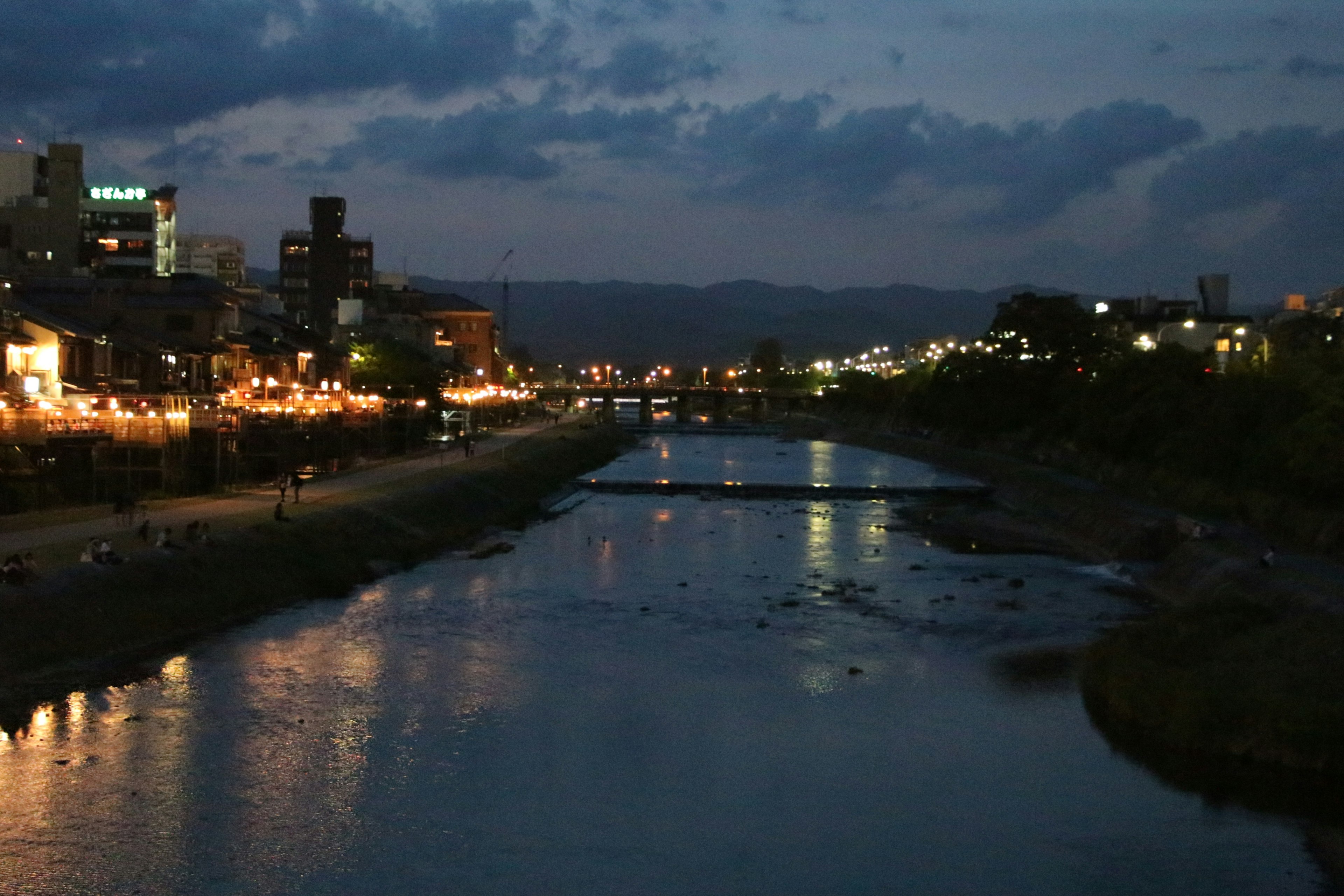 Vista nocturna de un río reflejando las luces de la ciudad