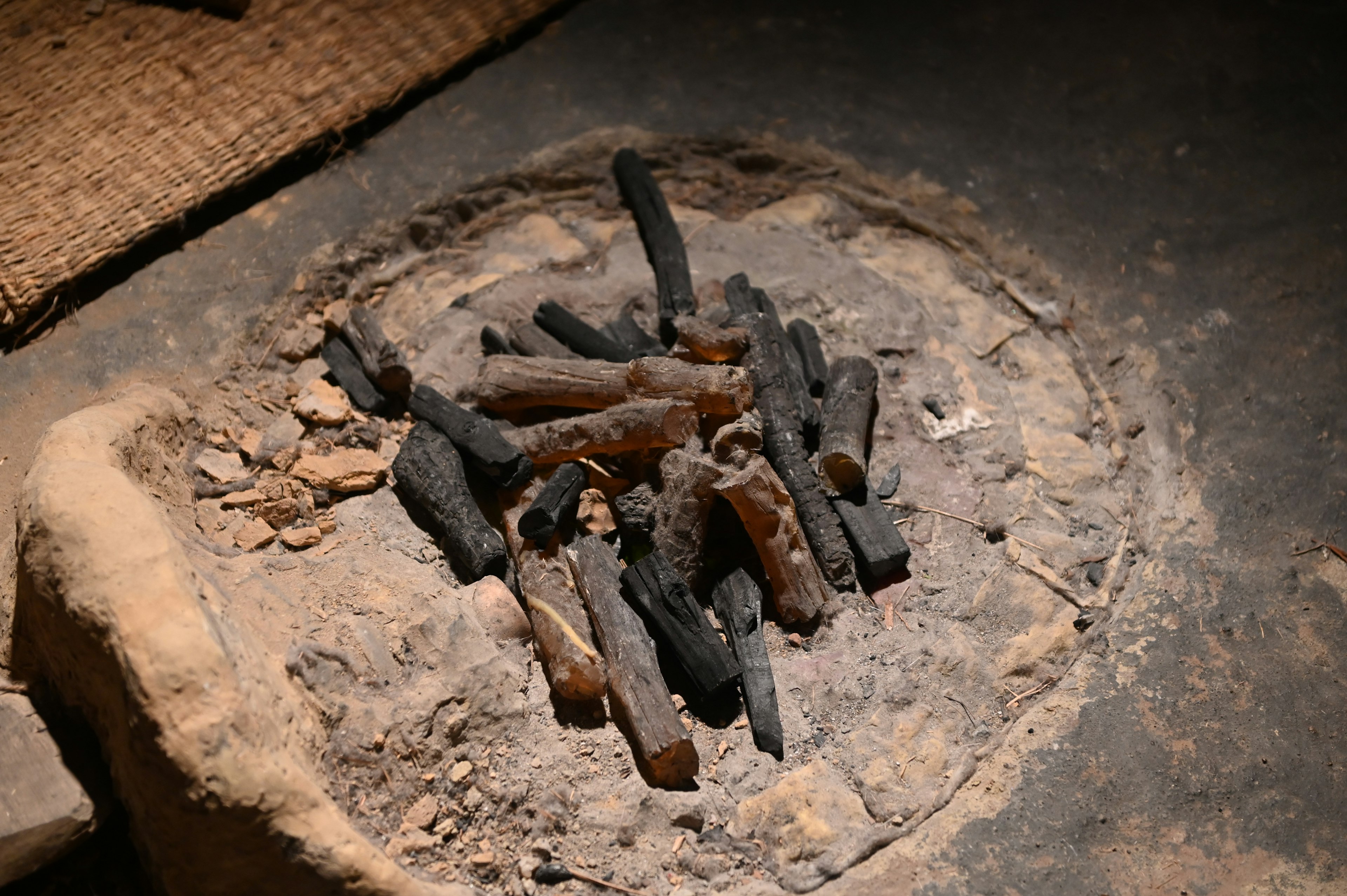 A bundle of charcoal on an old stove with surrounding clay and ashes