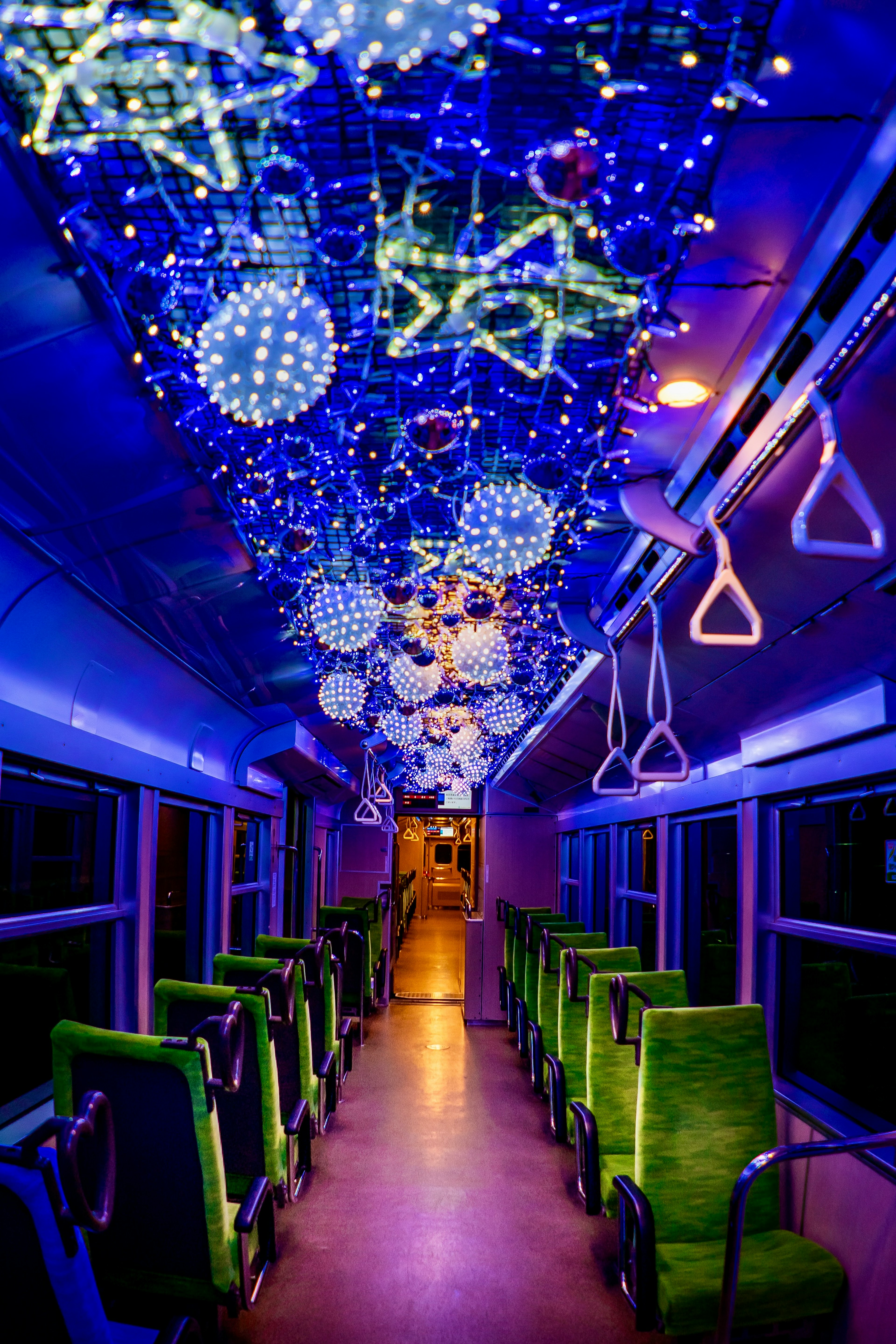 Interior of a train illuminated with blue lights featuring decorative hanging lights