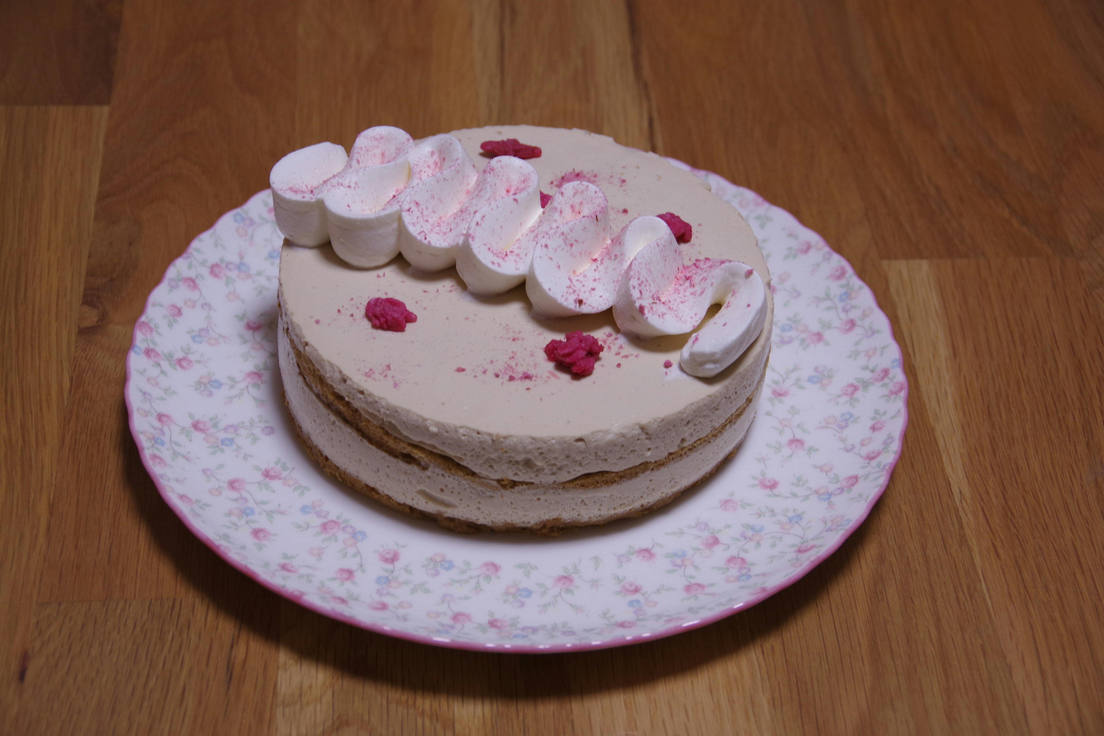 A cake topped with cream and marshmallows on a floral plate