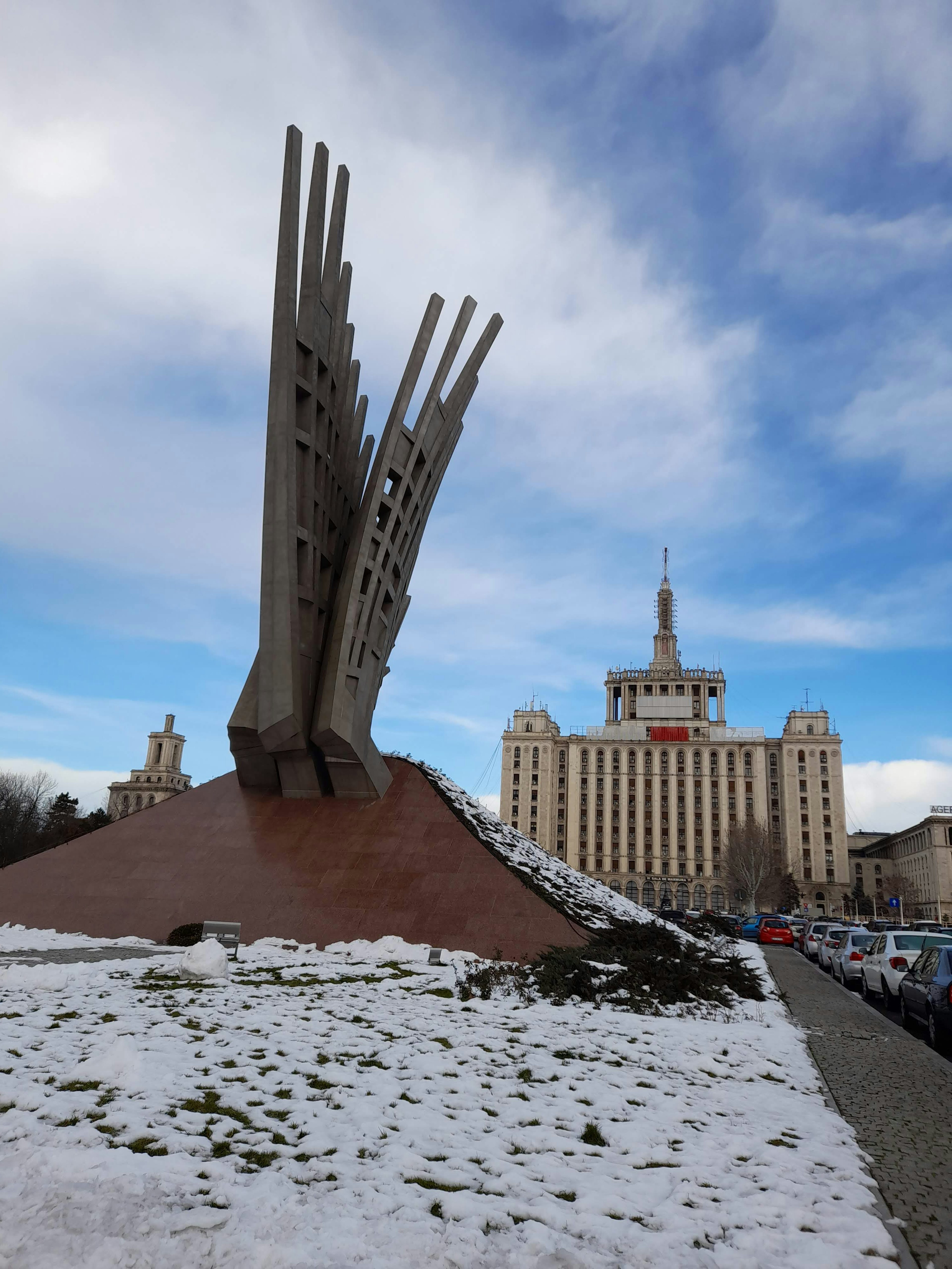 Monument in snow with a building in the background