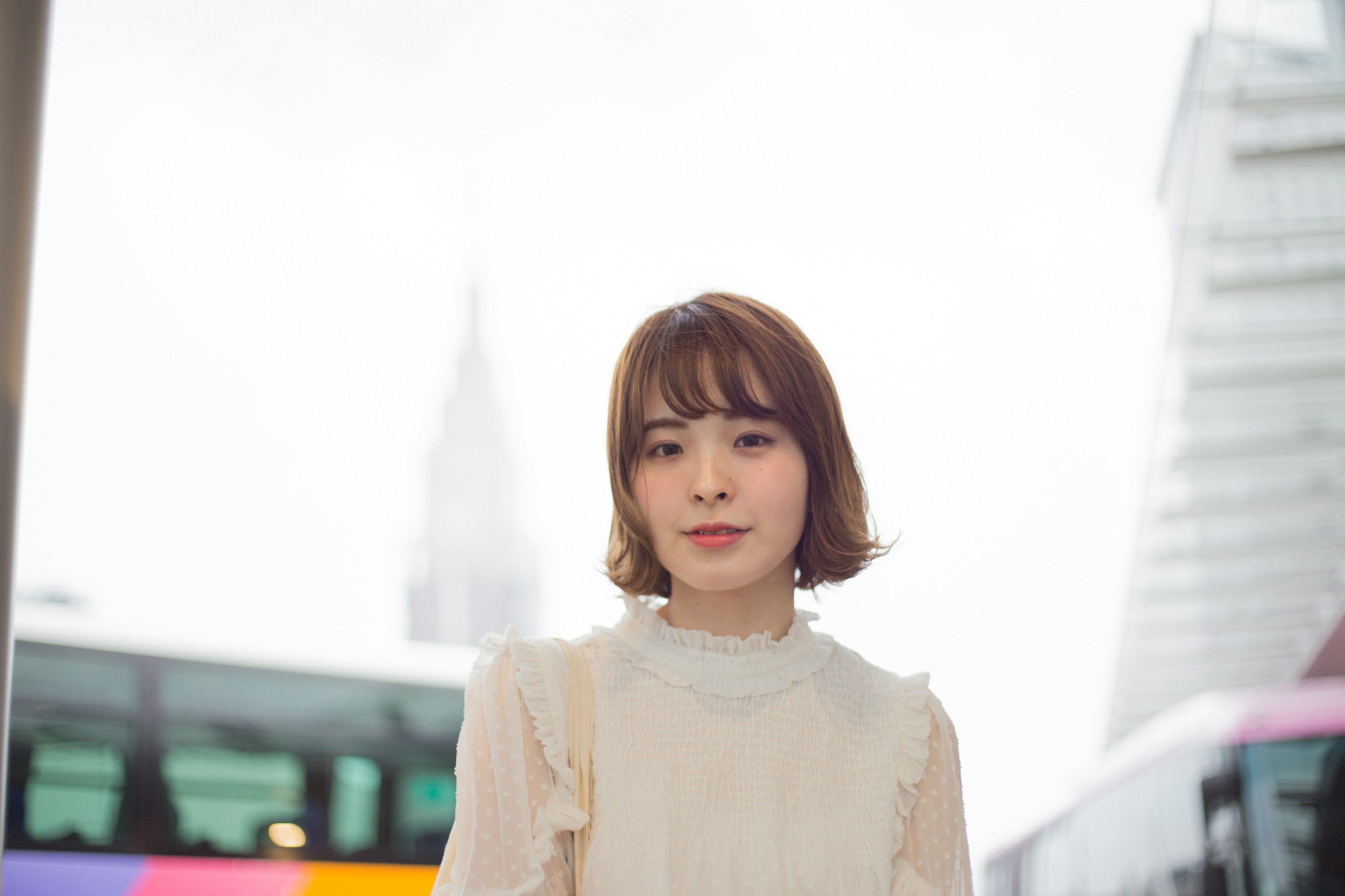 A woman in a light blouse standing in an urban setting