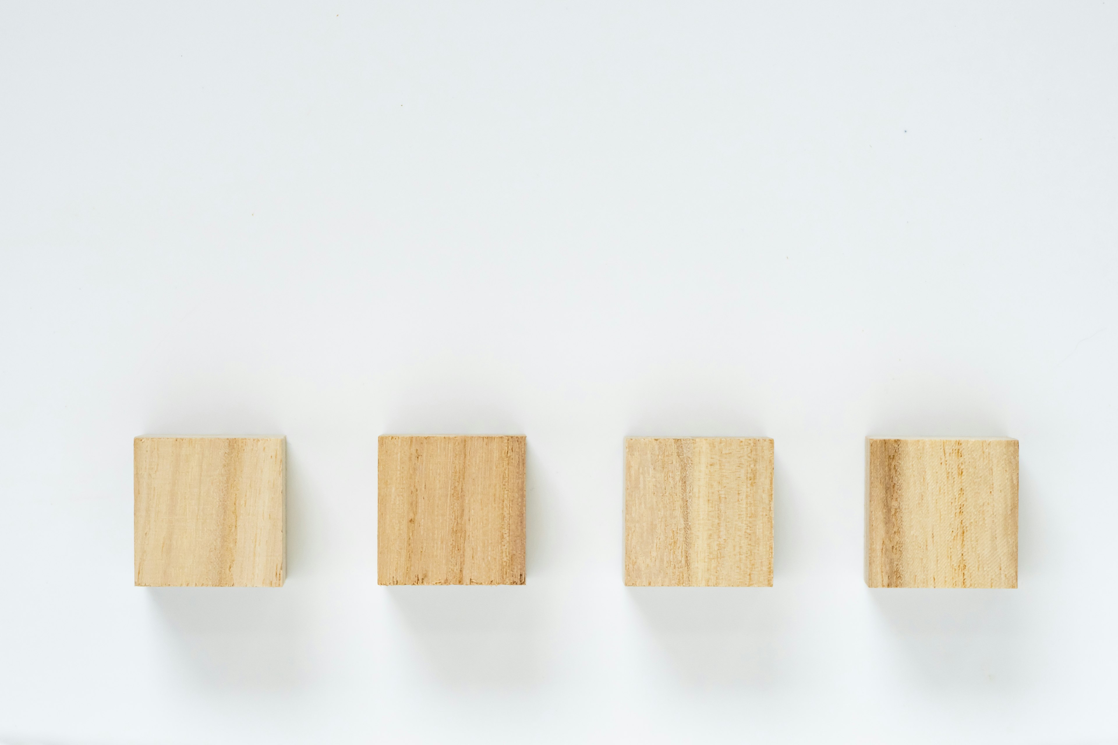 Quatre cubes en bois disposés sur un fond blanc