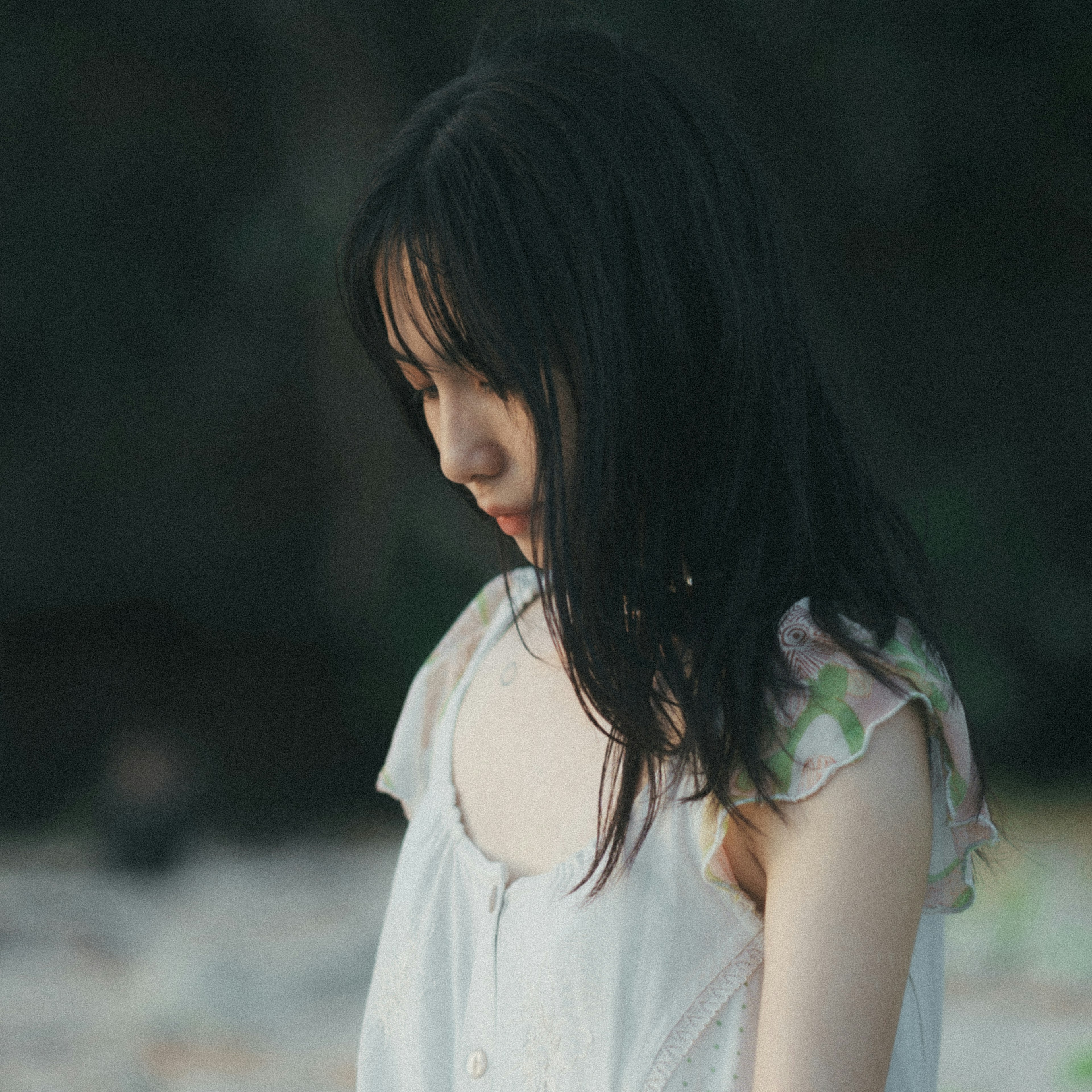 A young woman standing quietly wearing a light dress