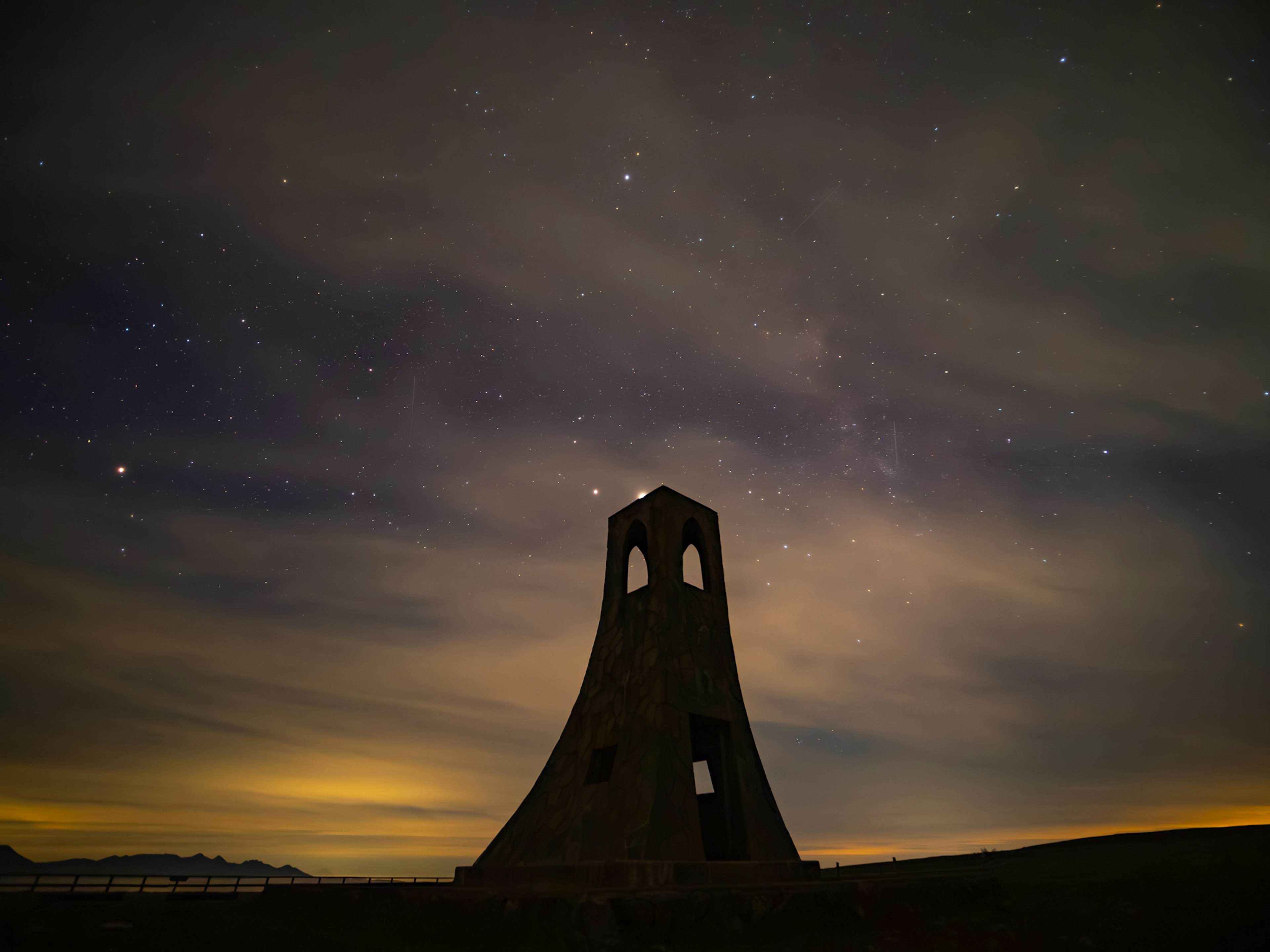 Silhouette menara tua di latar belakang langit berbintang