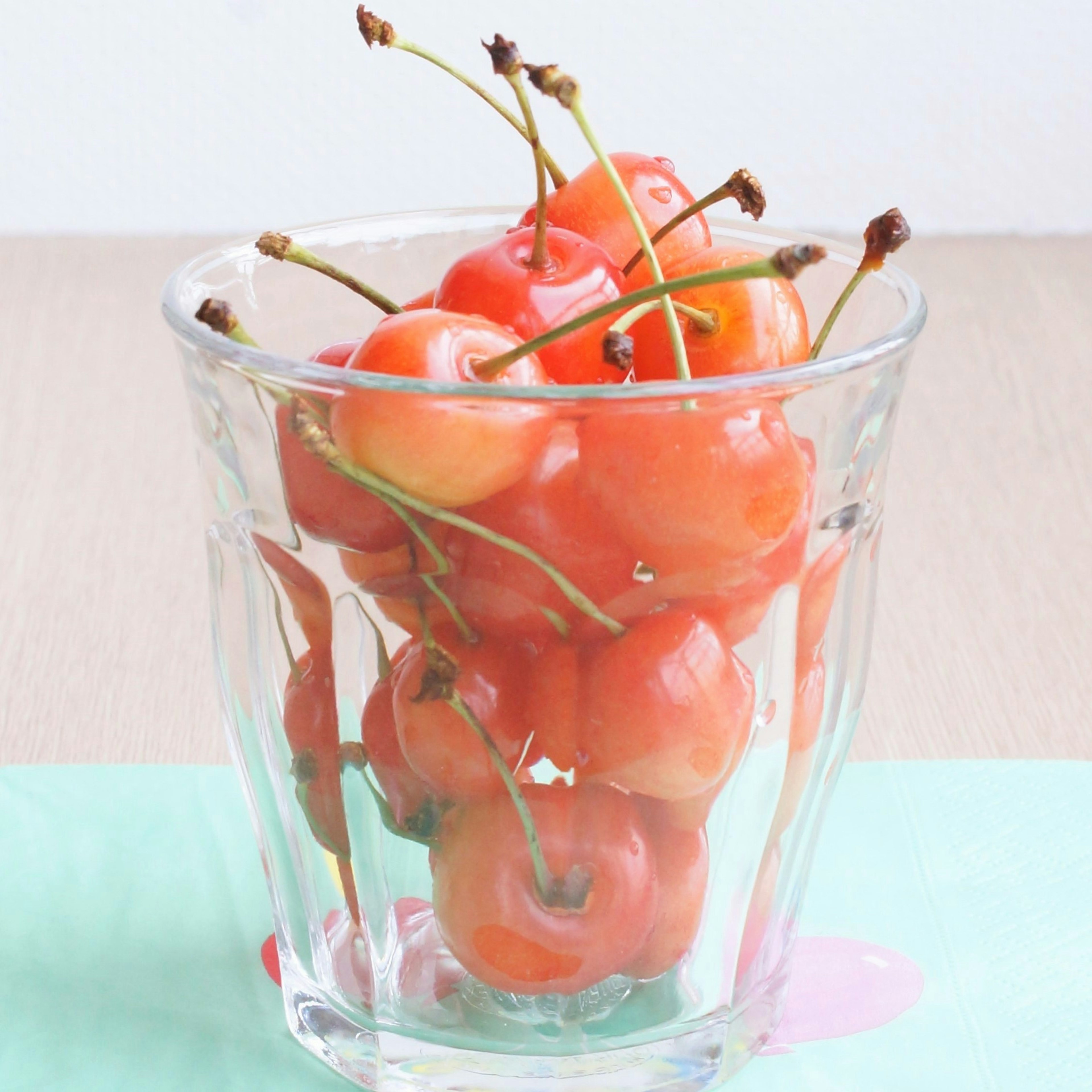 Rote kirschähnliche Früchte in einem klaren Glas