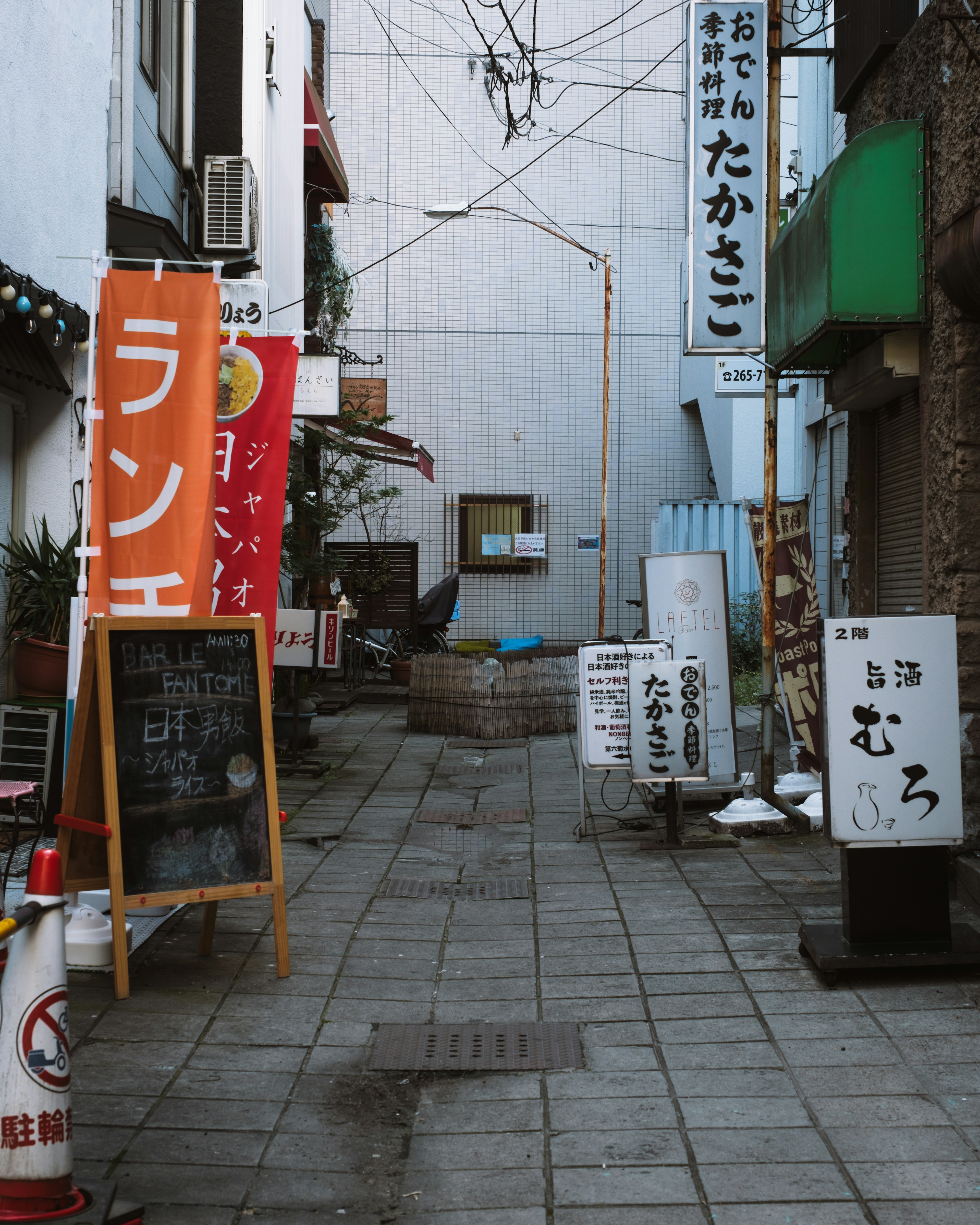 狭い路地に並ぶ飲食店の看板と舗装された道