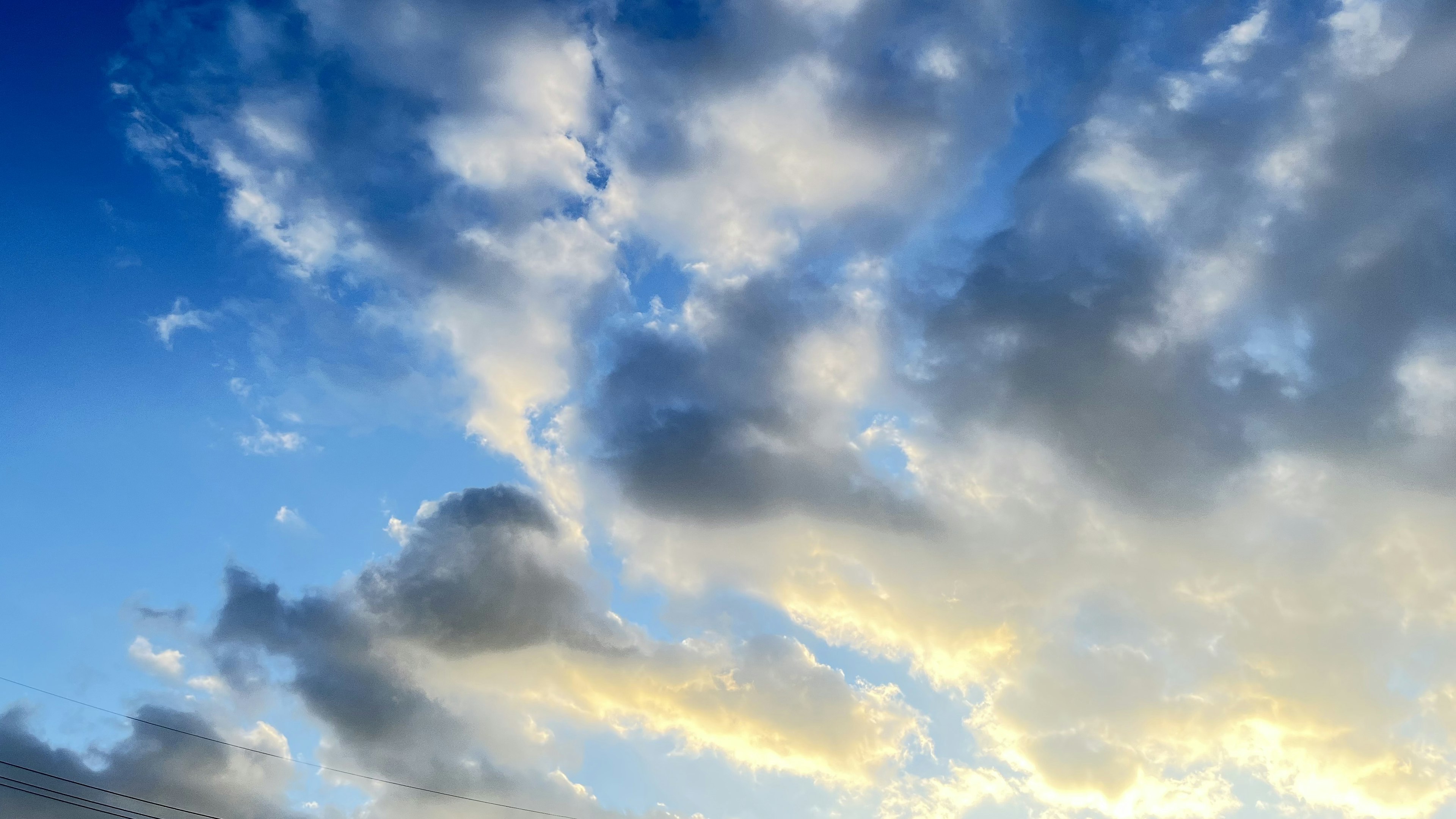 青空に浮かぶ白い雲とオレンジ色の光