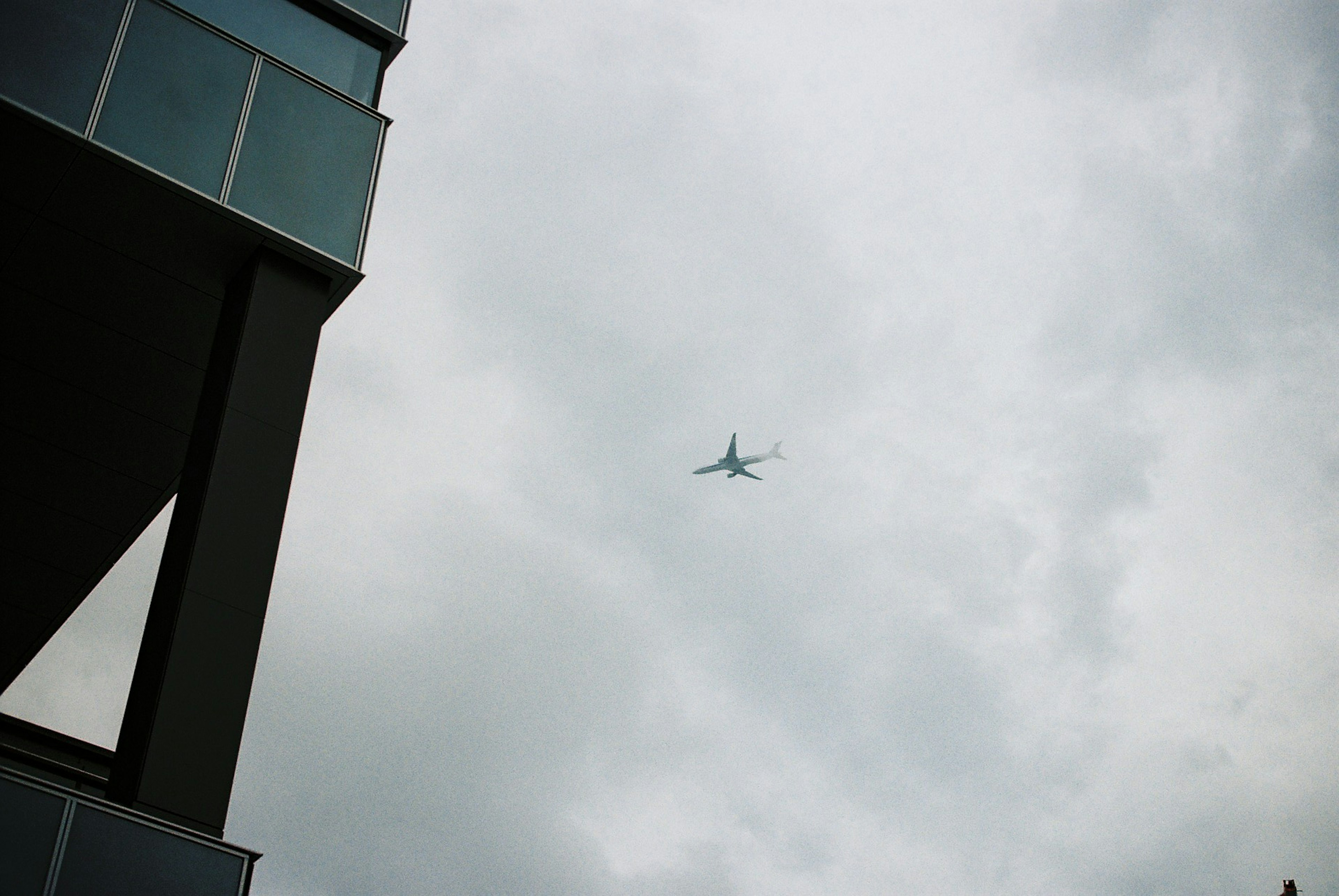 高層ビルの近くで飛行機が雲の中を飛んでいる