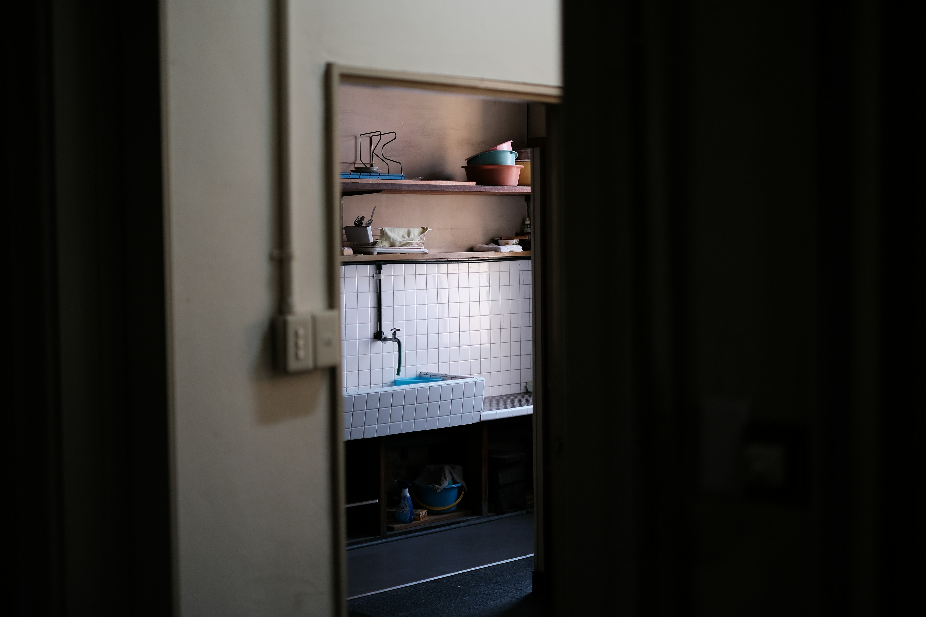 Bright kitchen sink and shelves visible from a dark hallway