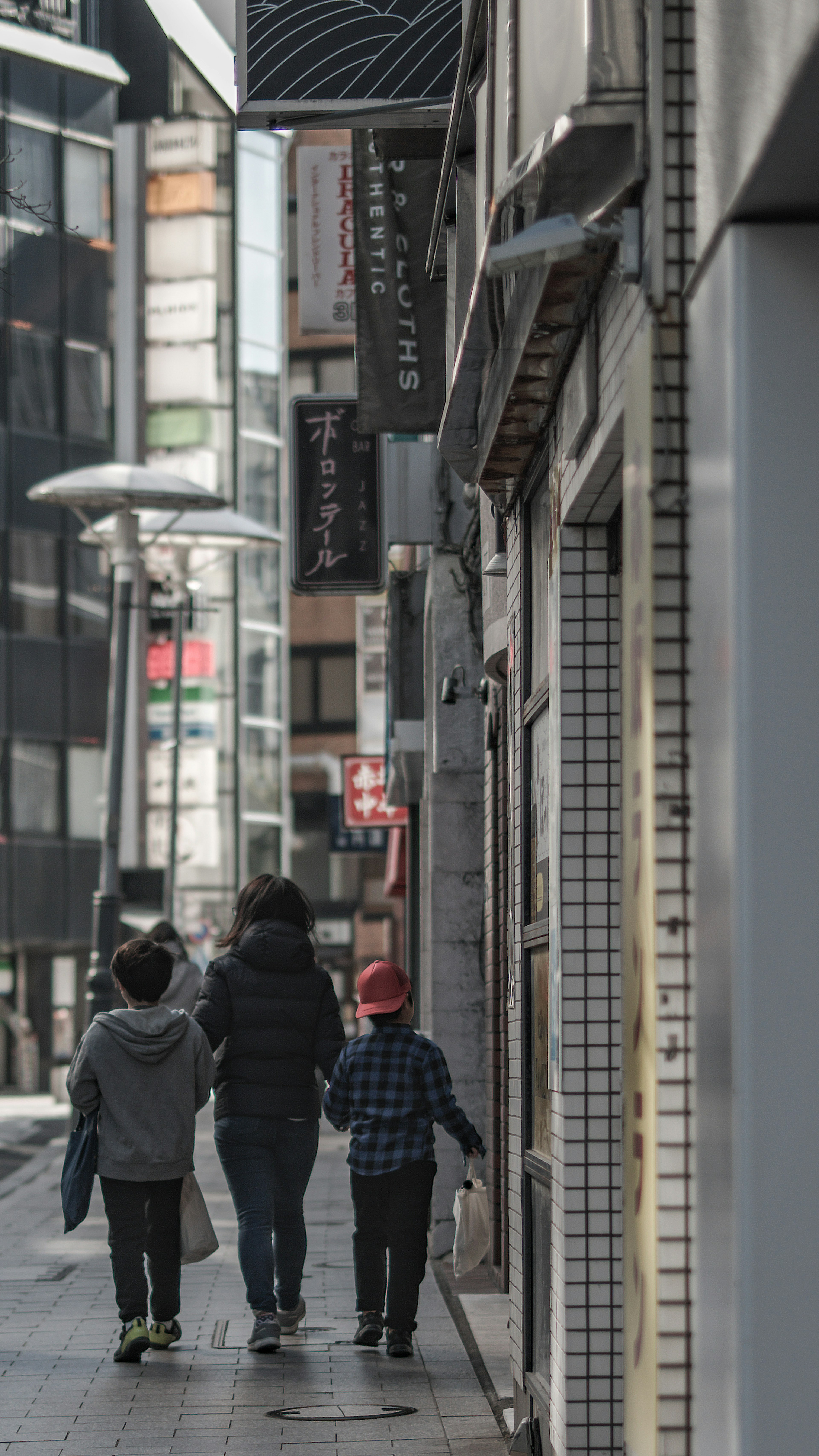 Group of adults and children walking on a city street modern buildings and signs in the background