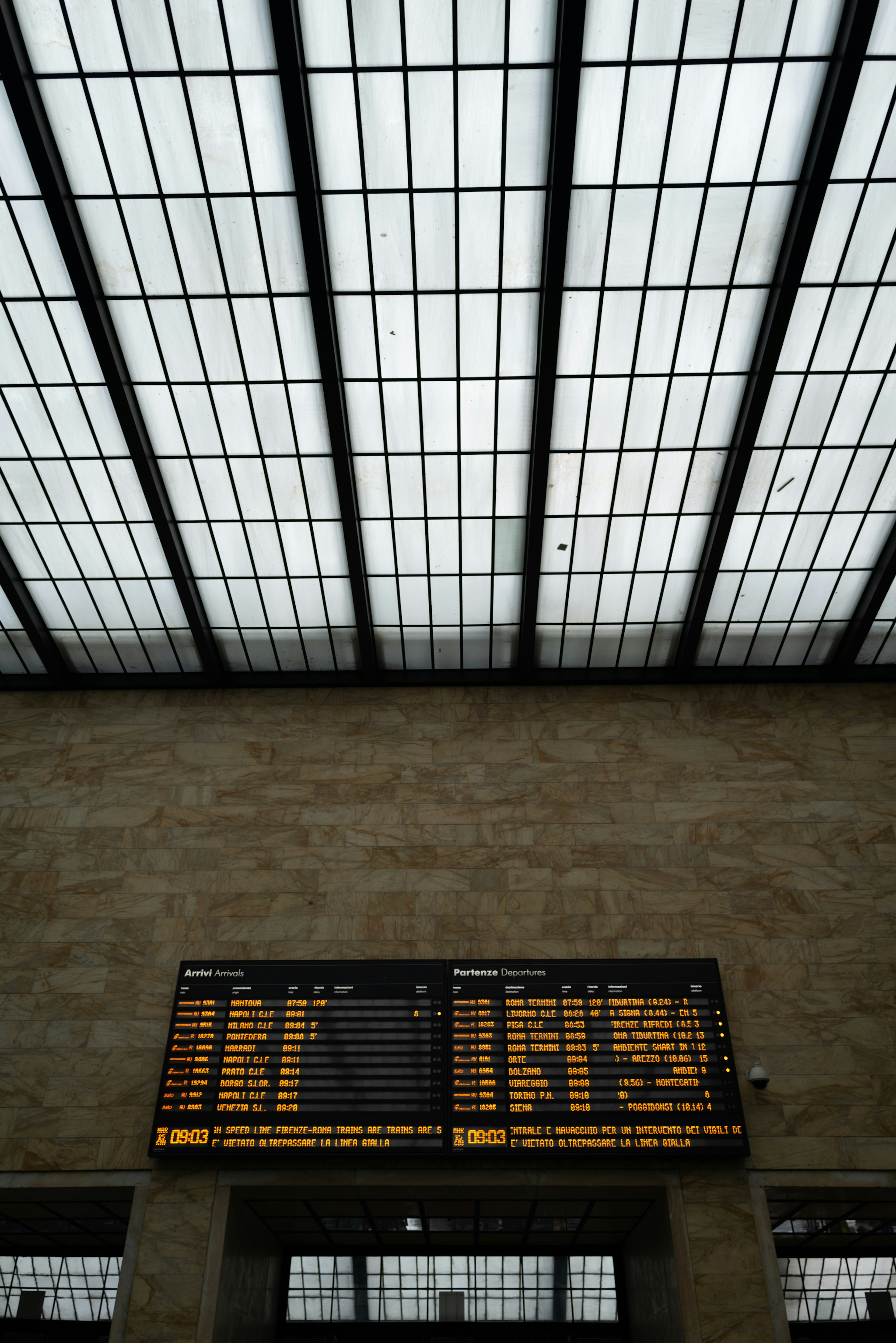 Interno di una stazione ferroviaria con il soffitto e un tabellone delle partenze