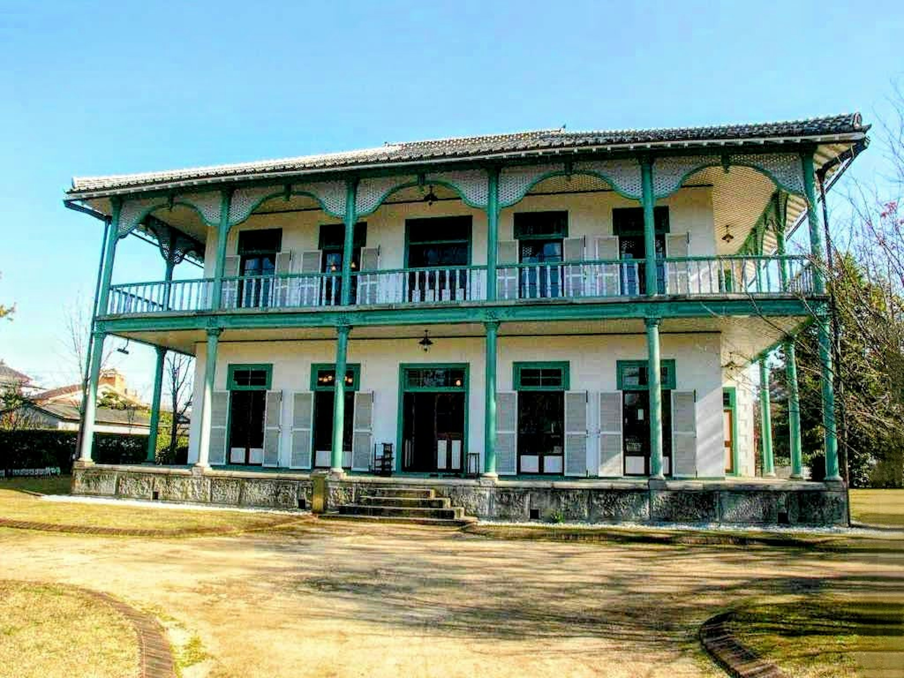 Bâtiment en bois à deux étages de couleur bleue et blanche avec un large balcon et des escaliers