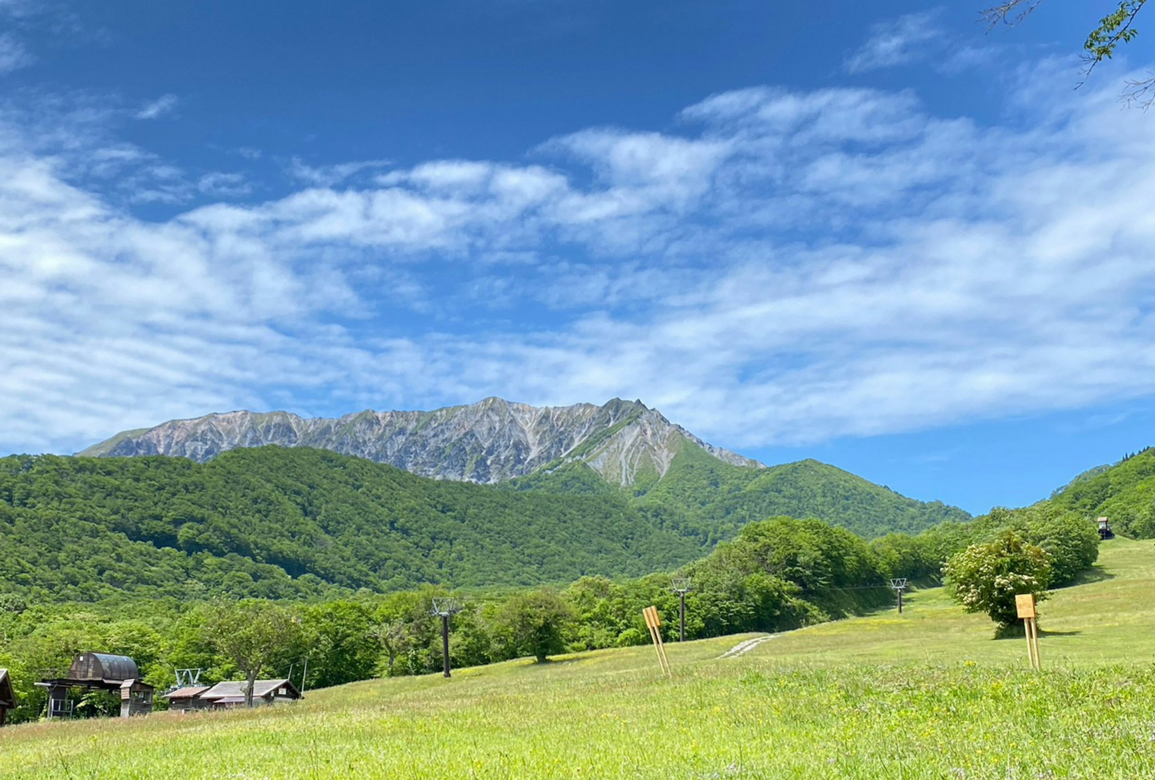 Malersicher Blick auf grüne Berge und Wiesen unter einem blauen Himmel mit weißen Wolken