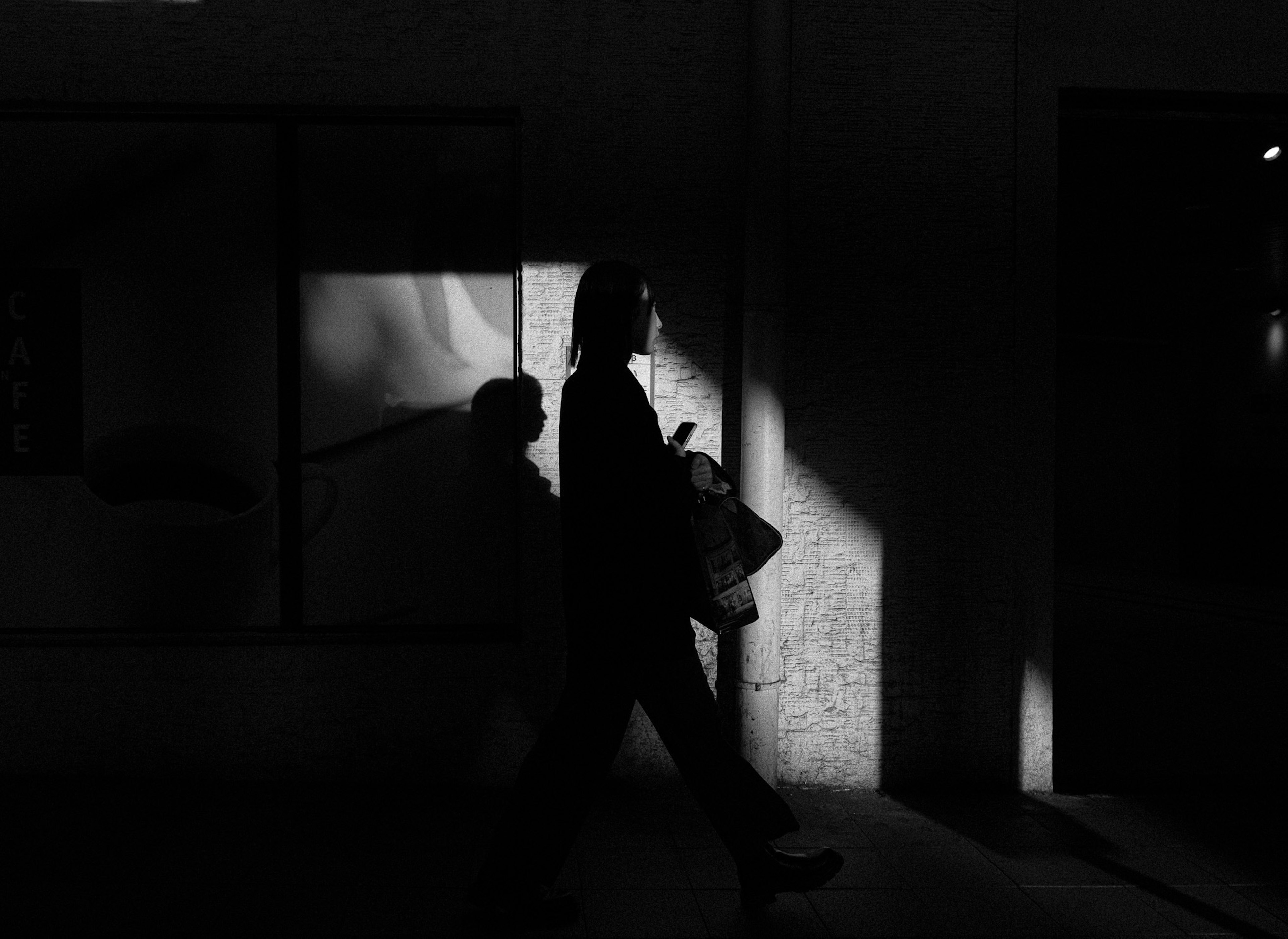 Silhouette, die auf einer dunklen Straße mit Schattenreflexionen läuft