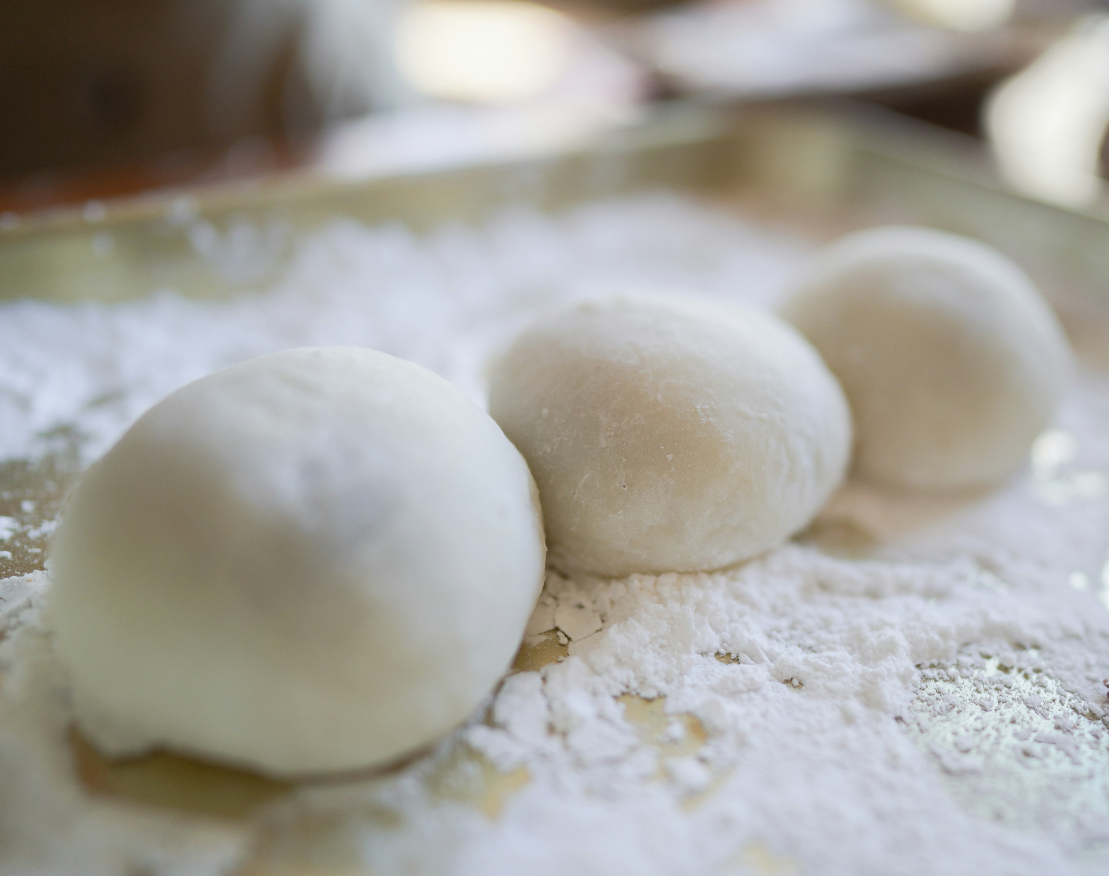 Three white dumplings arranged on powdered sugar