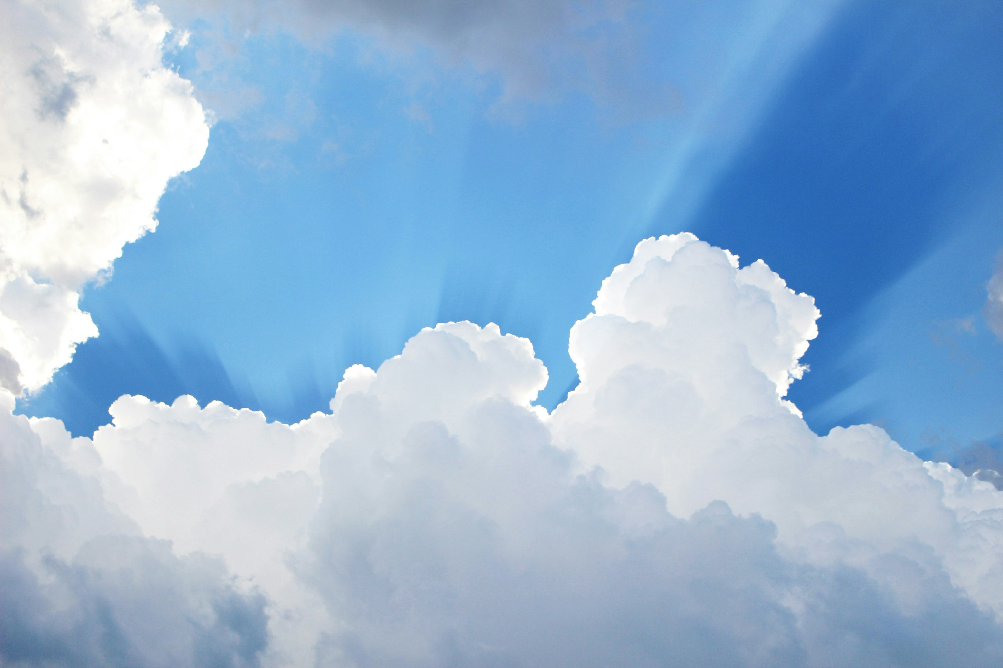 Helle weiße Wolken mit Lichtstrahlen vor blauem Himmel