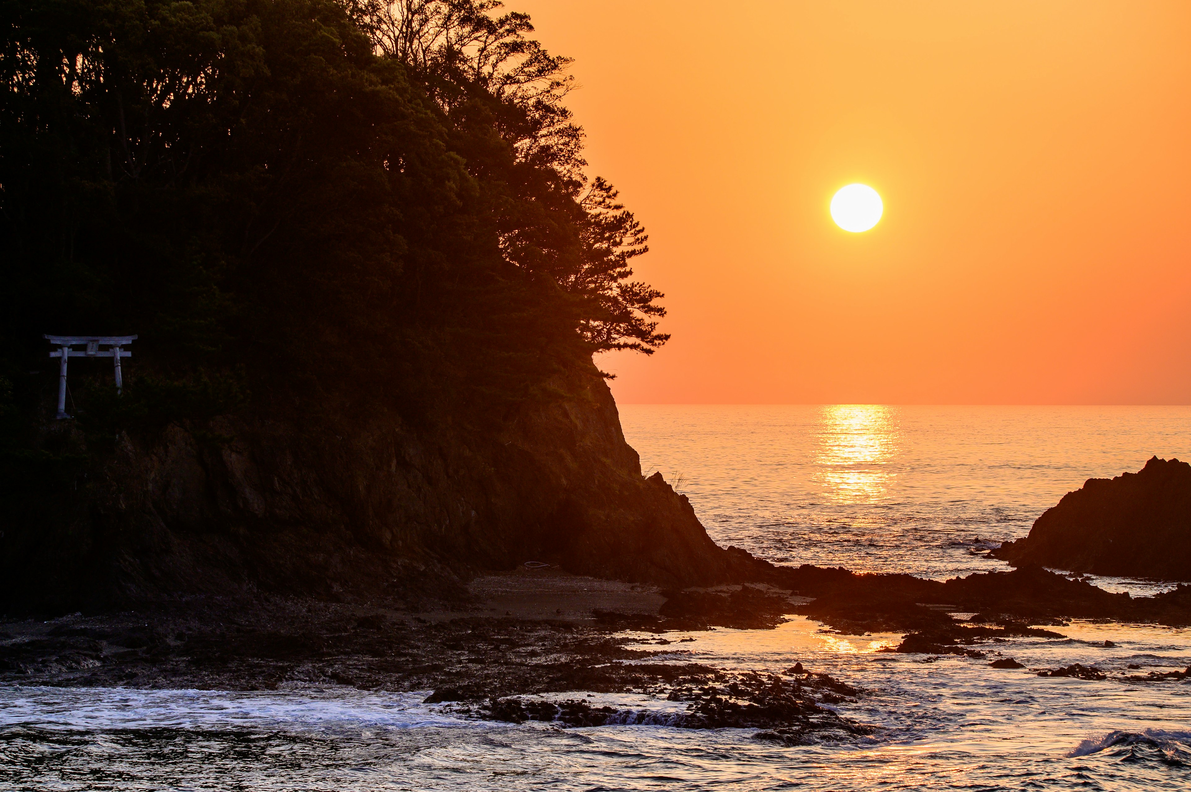 夕日が海に沈む美しい風景 岩の上に鳥居が見える