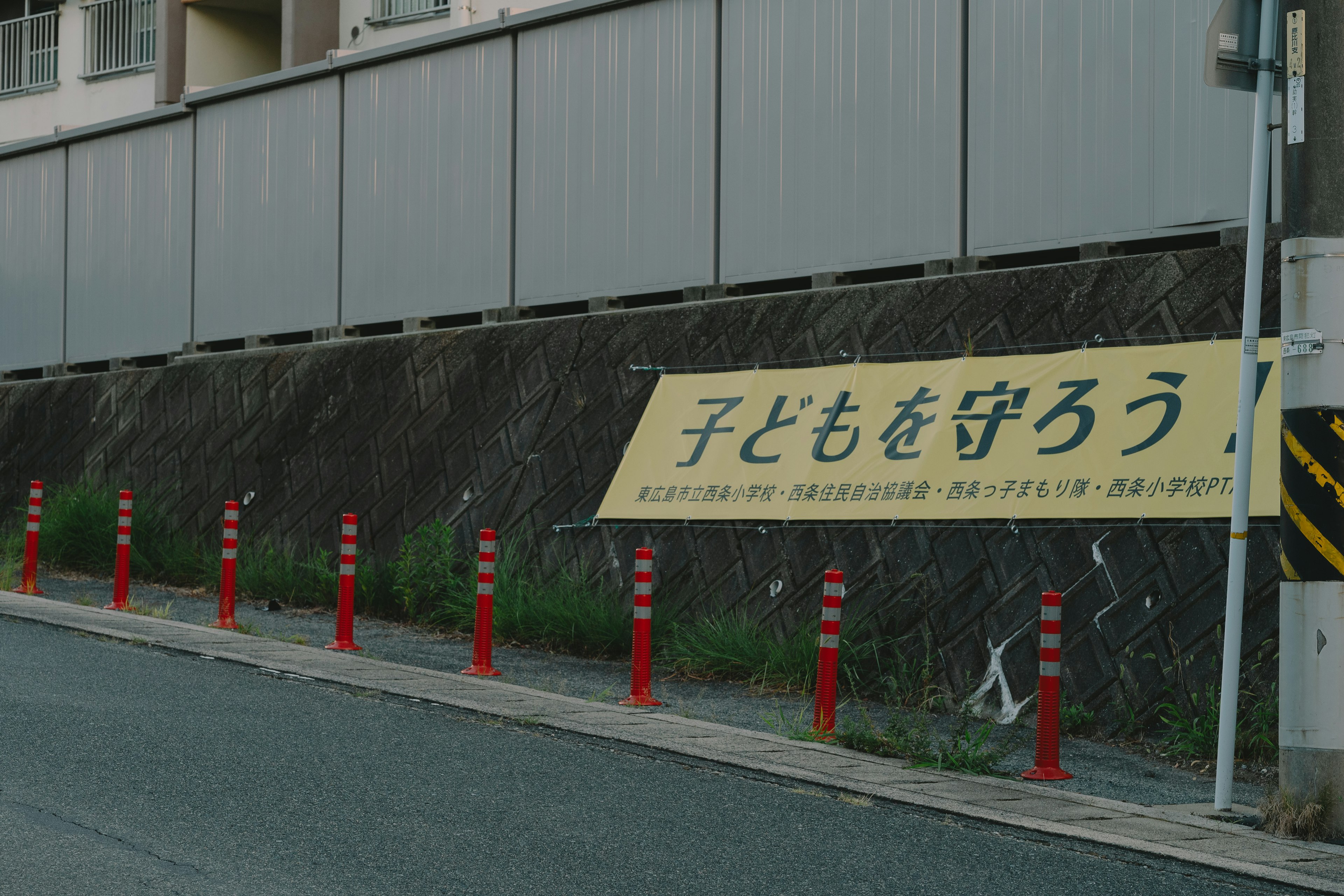 A sign promoting child safety with red poles lining the road