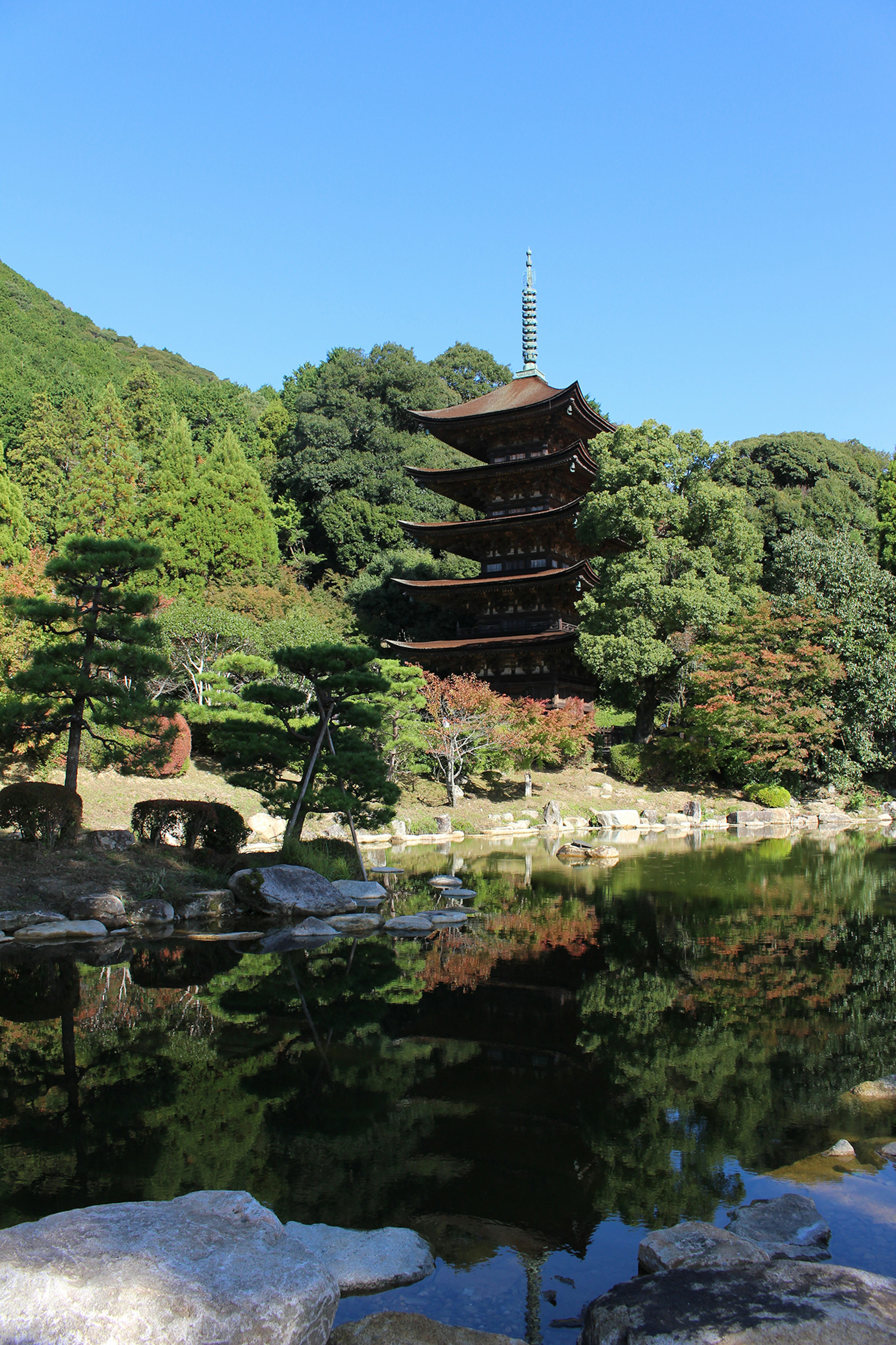 Vista scenica di una pagoda giapponese tradizionale circondata da una vegetazione lussureggiante riflessa in uno stagno