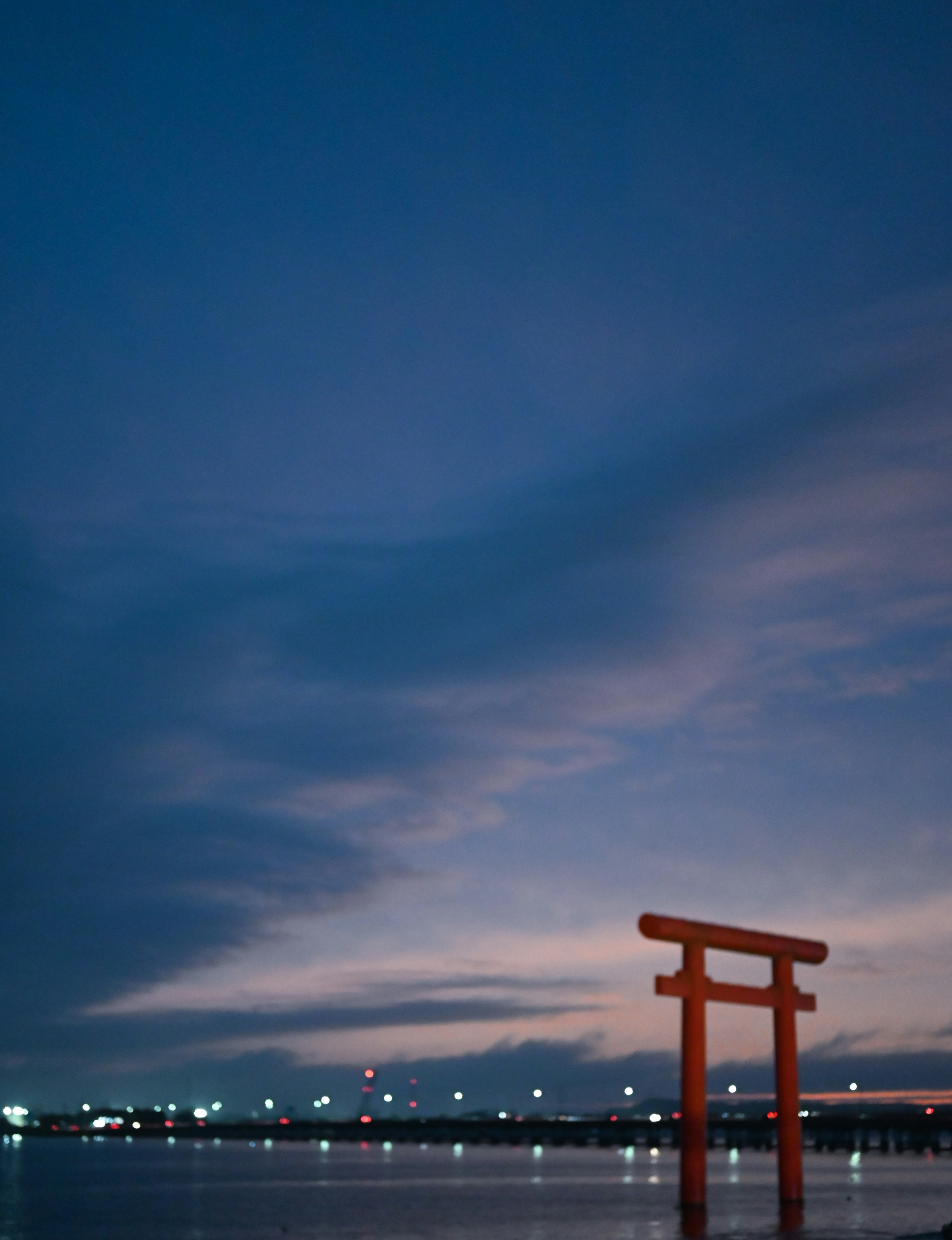 Gerbang torii merah yang memantul di atas air saat senja