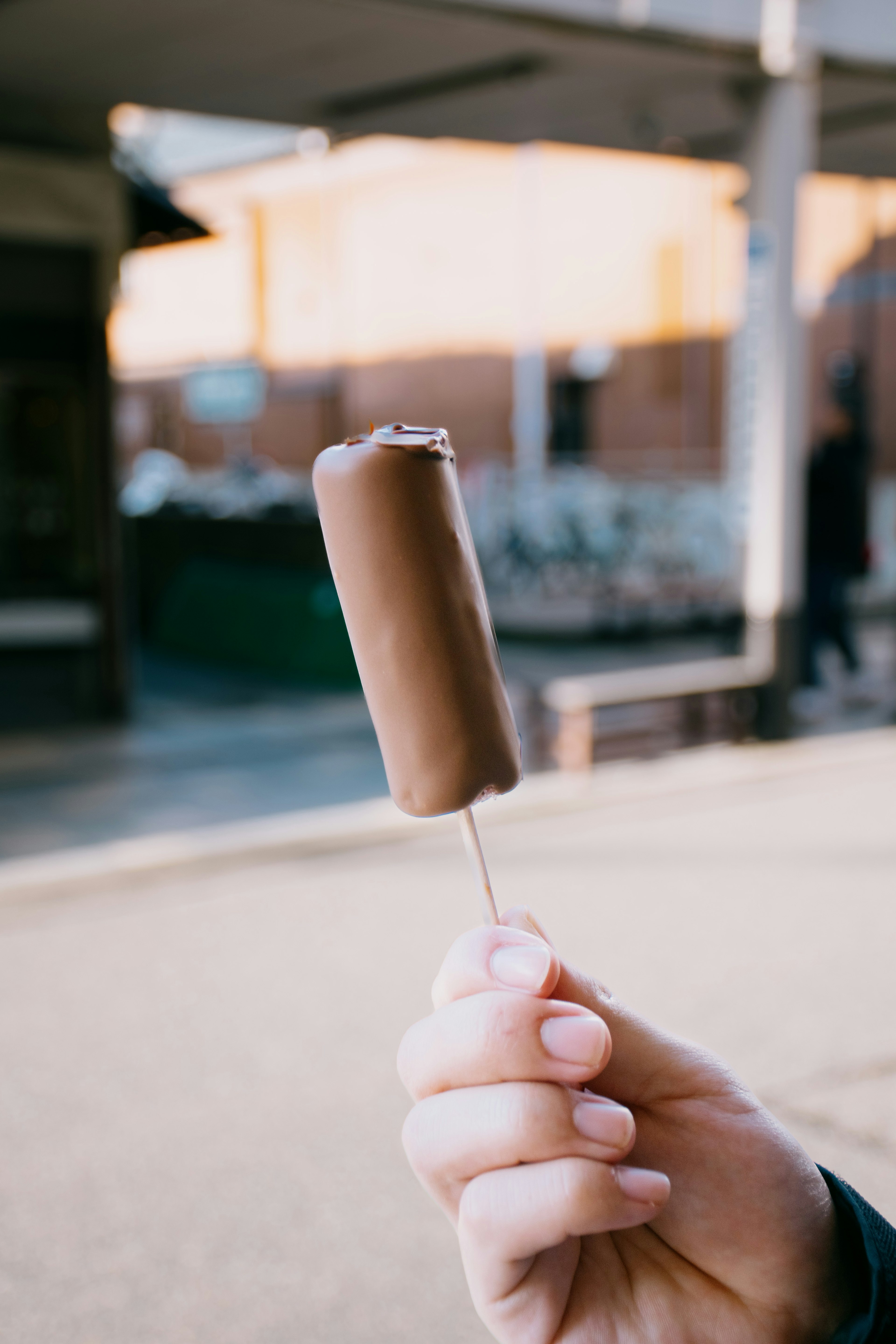 Une personne tenant une glace au chocolat sur un bâton