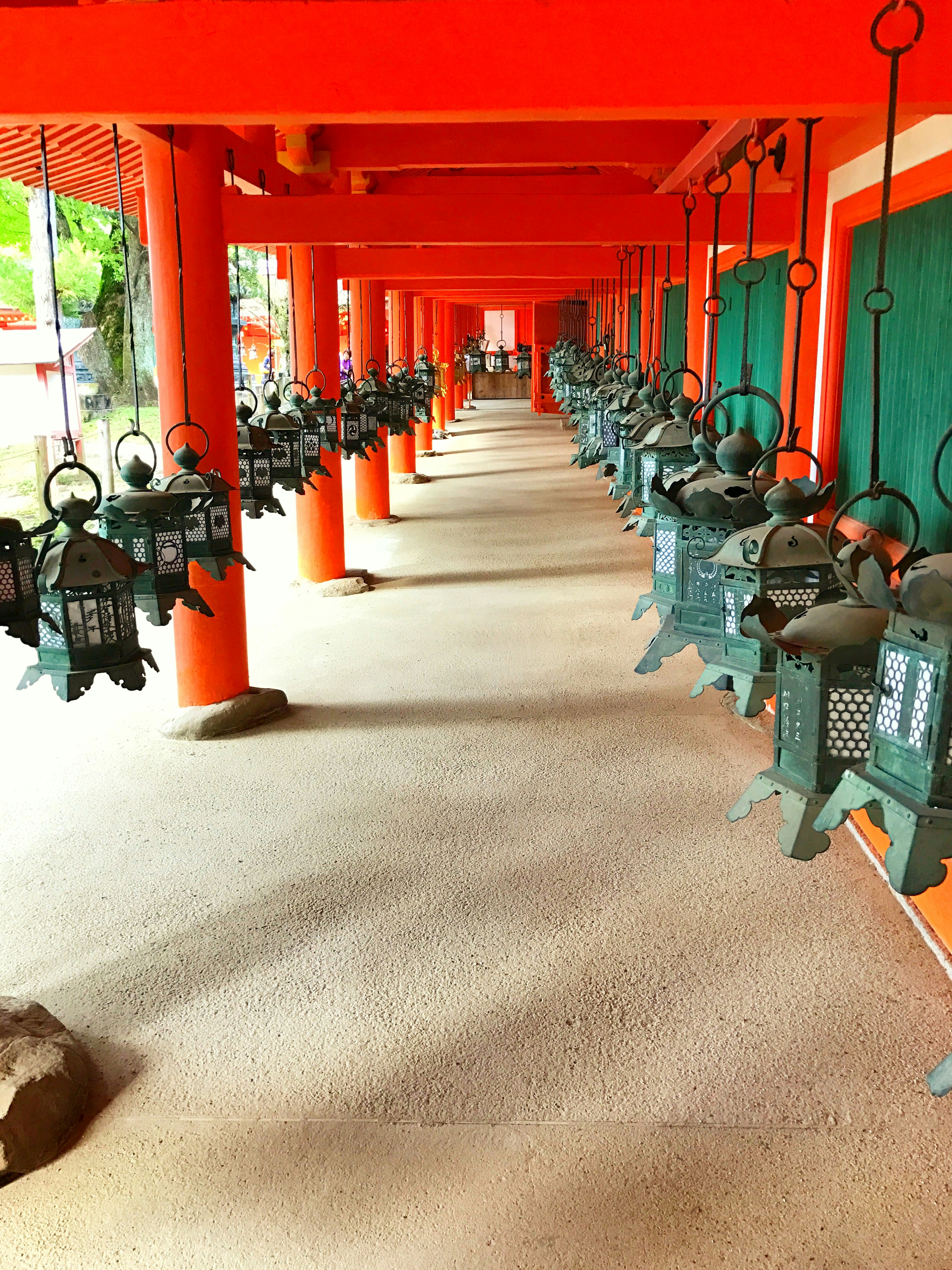 Row of bronze lanterns beneath red pillars