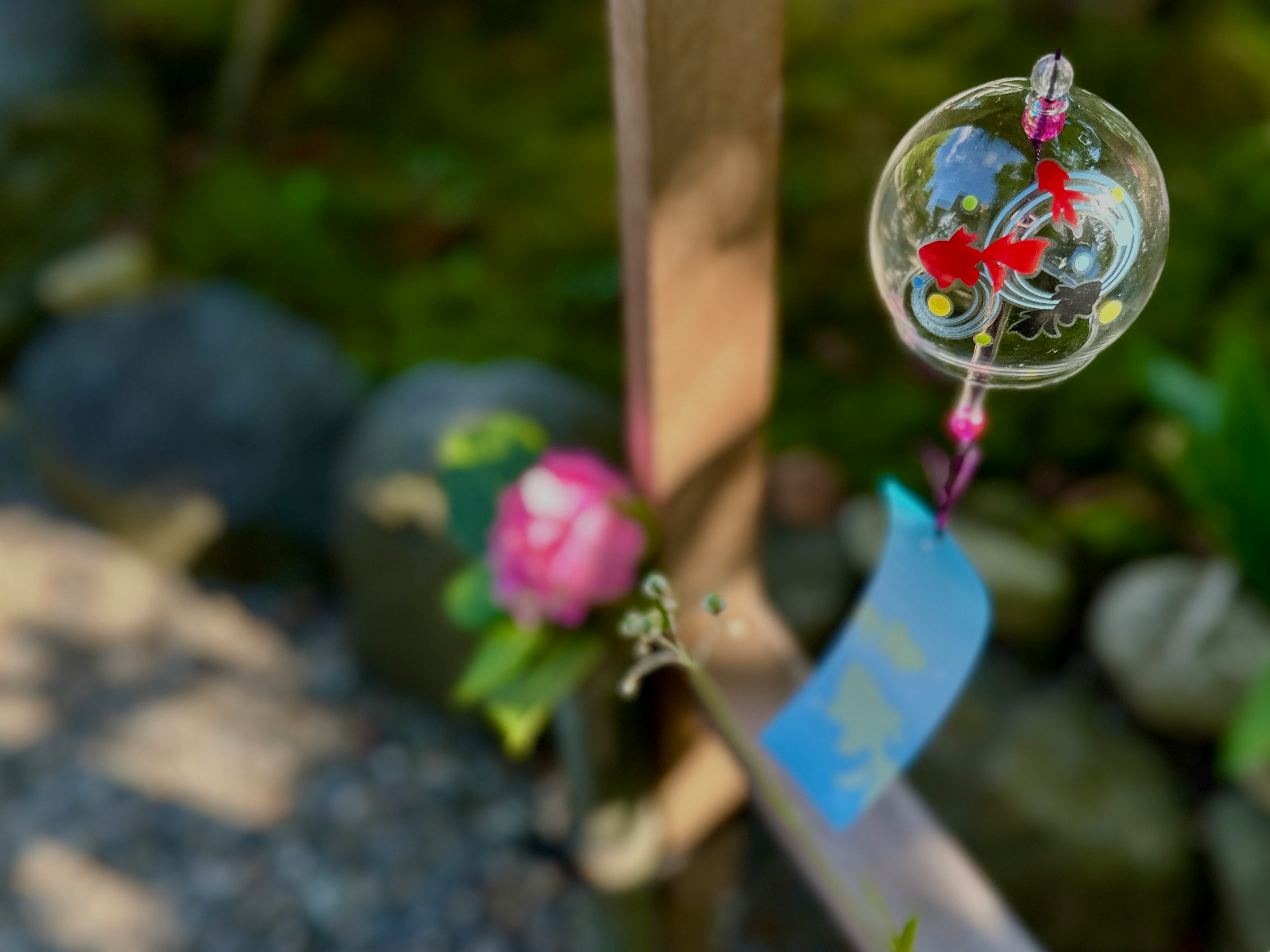 Eine Windglocke mit floralen Motiven, die in einem japanischen Garten hängt