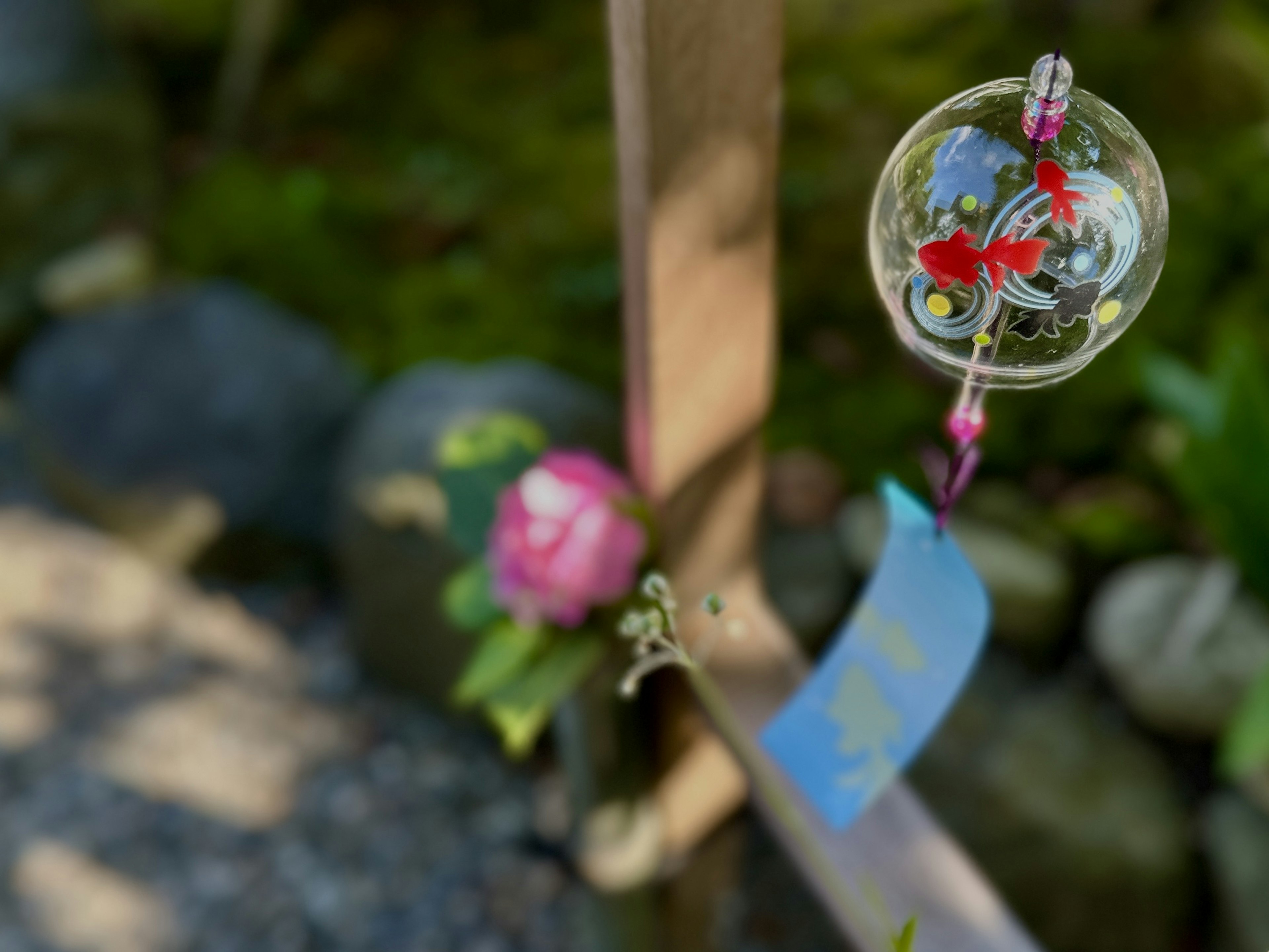 A wind chime with floral designs hanging in a Japanese garden