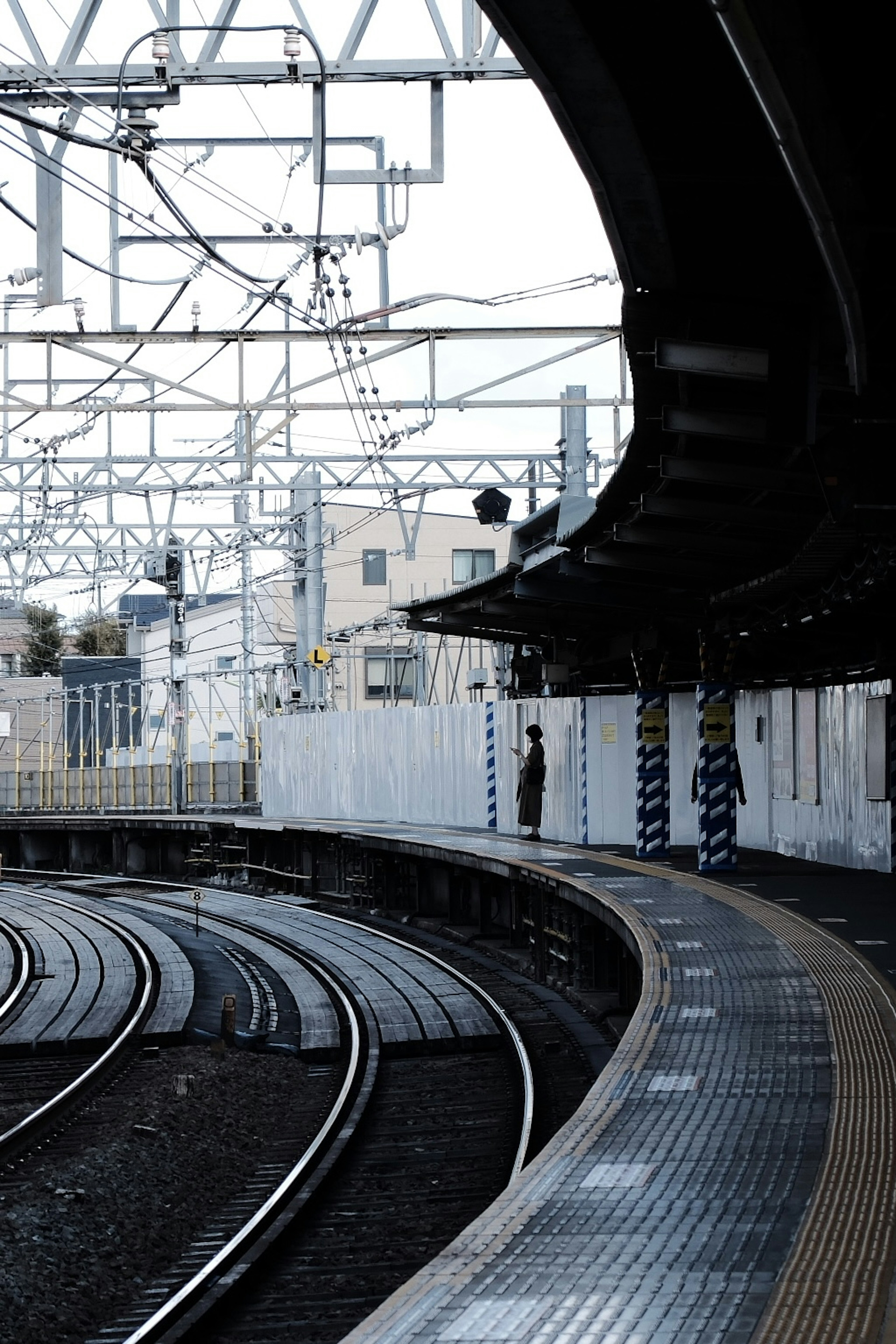 Pemandangan stasiun yang menunjukkan platform melengkung dan rel kereta