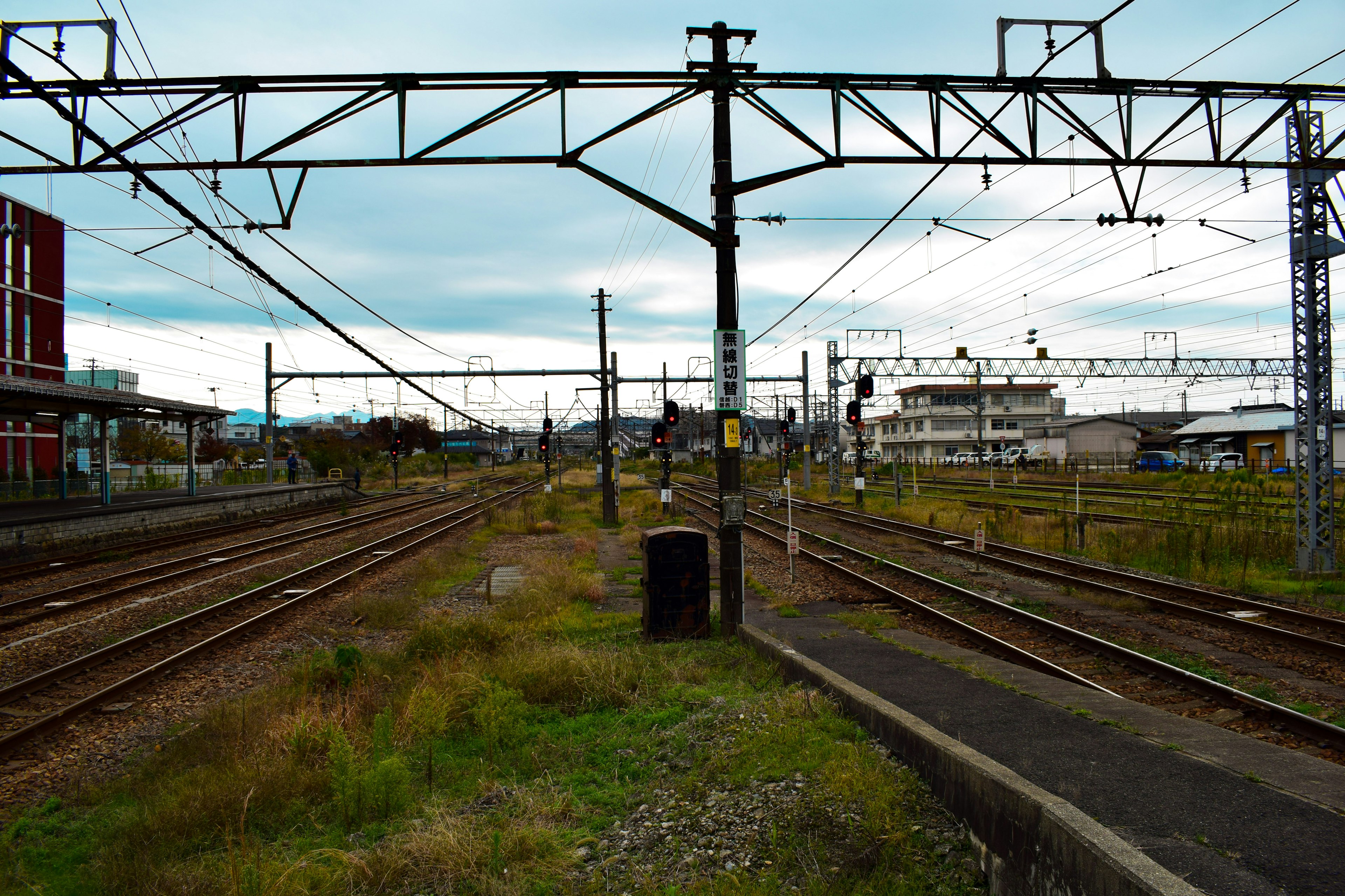 รางรถไฟและสายไฟฟ้าในทิวทัศน์ที่มีท้องฟ้ามืดครึ้มและพื้นที่หญ้า