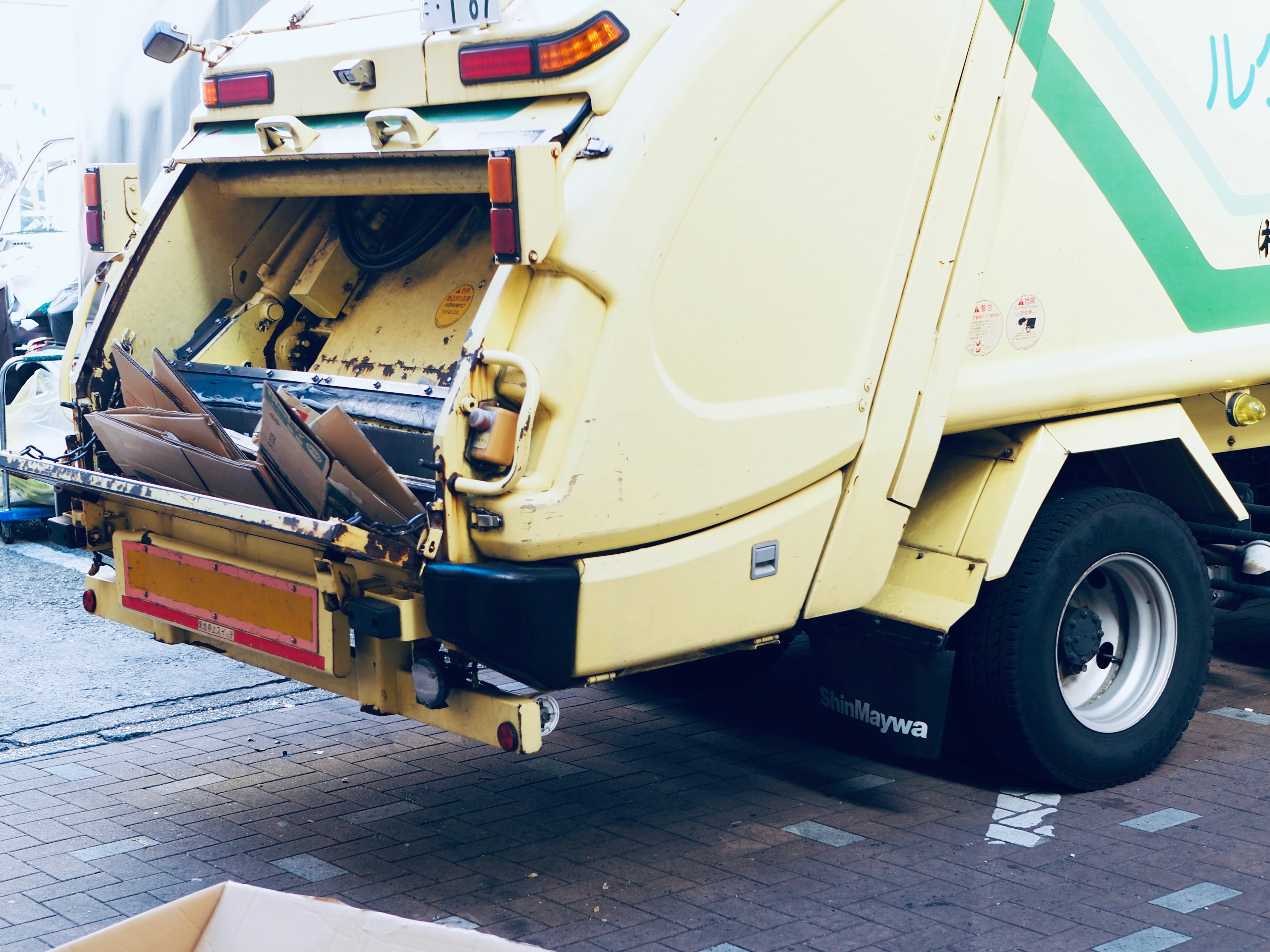 Truk sampah kuning dengan kompartemen belakang terbuka