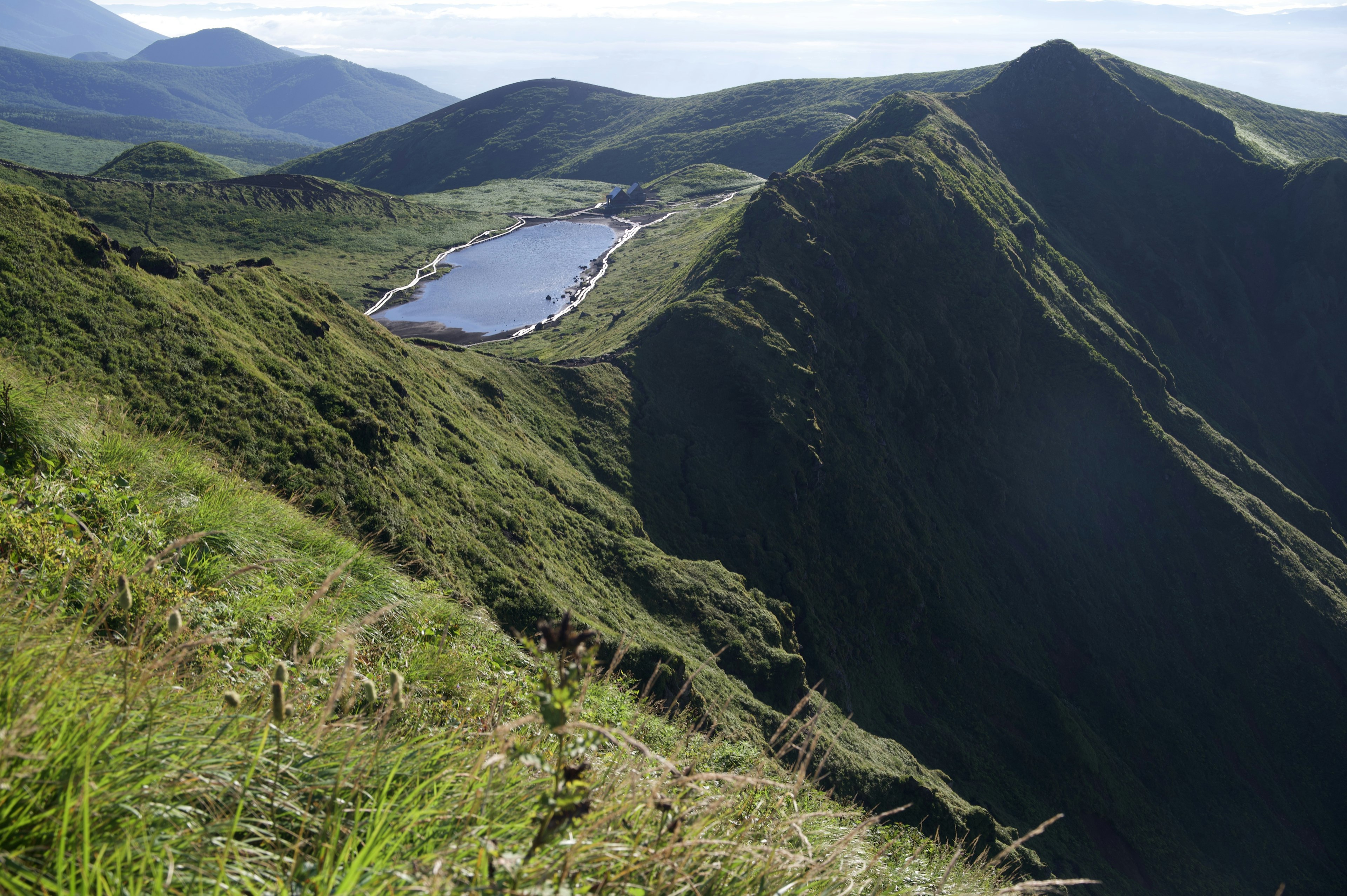 宁静湖泊的风景，四周环绕着绿色山丘和山脉