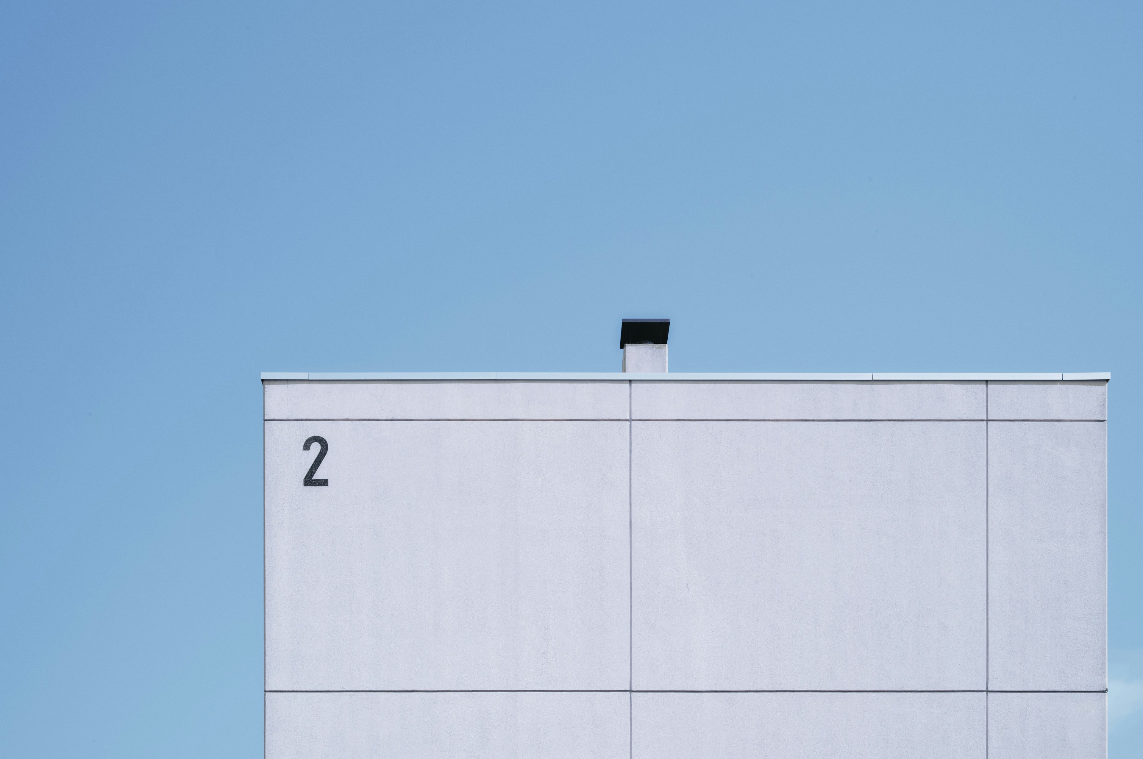 Partie d'un bâtiment blanc sous un ciel bleu avec le numéro 2