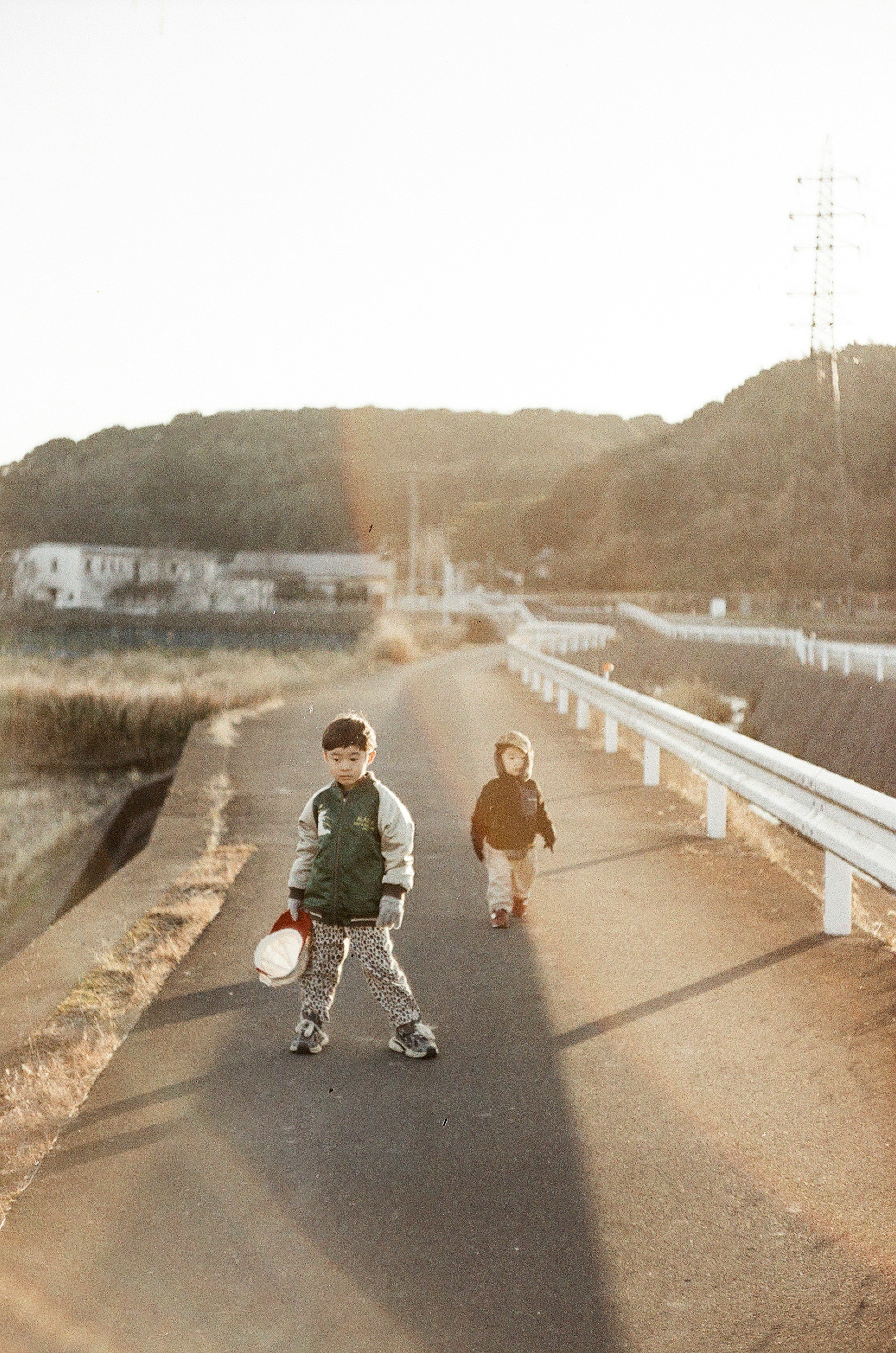 Two children walking on a sunset road