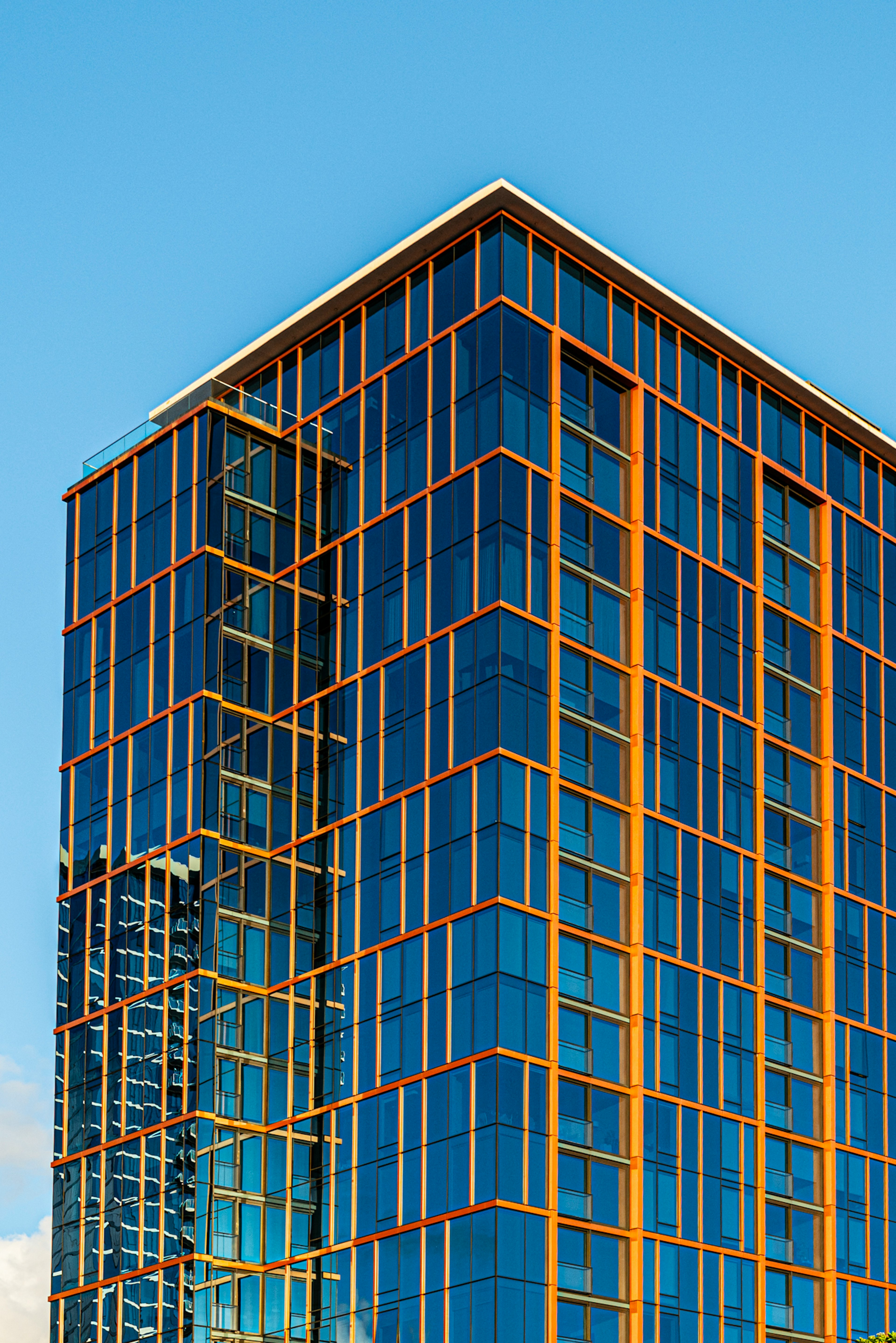 Coin d'un gratte-ciel moderne avec un encadrement orange sous un ciel bleu dégagé