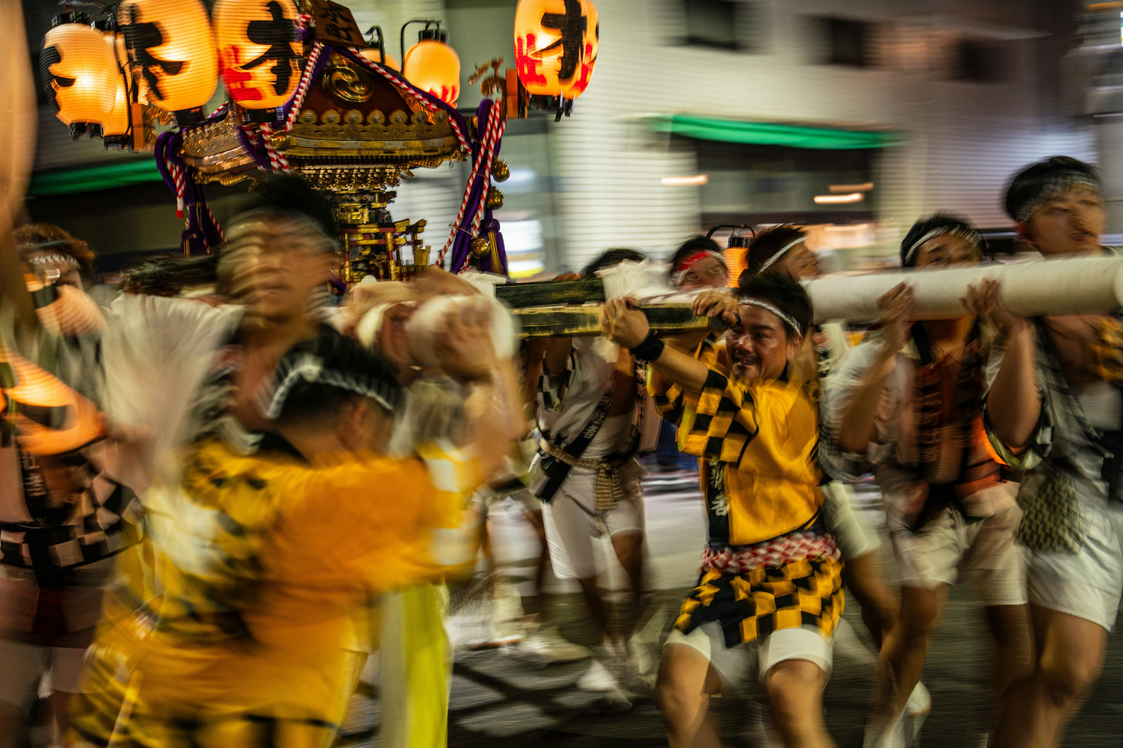 Vibrant scene of people carrying a portable shrine during a night festival