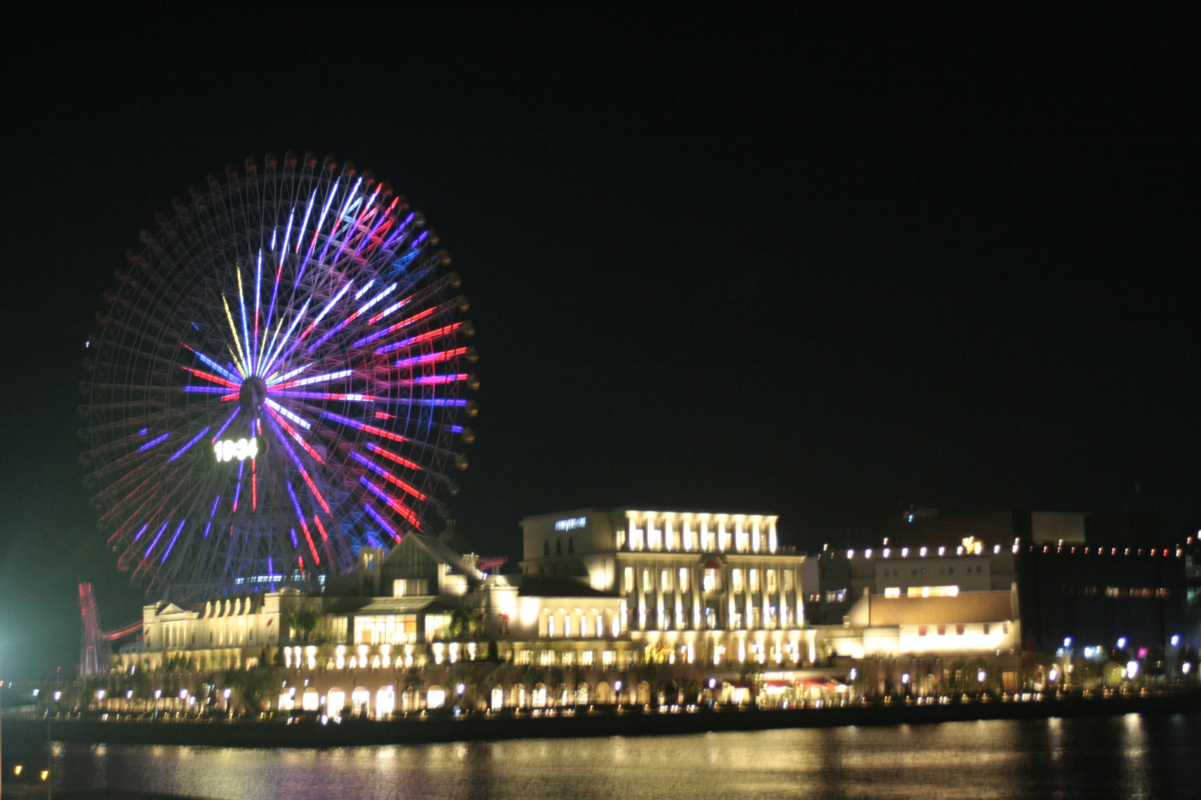 Night view of a colorful Ferris wheel and illuminated buildings