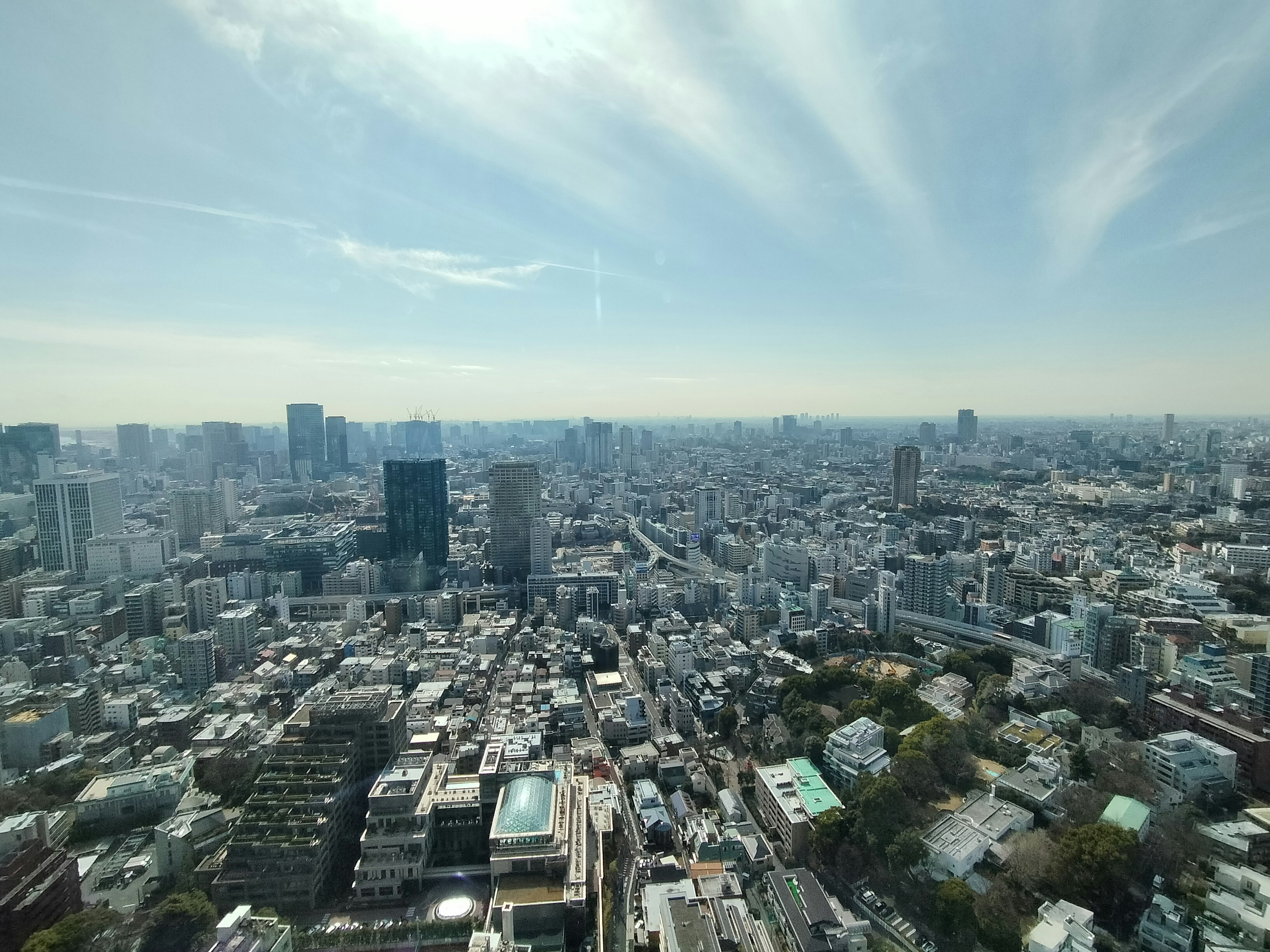 Panoramic view of Tokyo cityscape from a high-rise building featuring blue sky and clouds