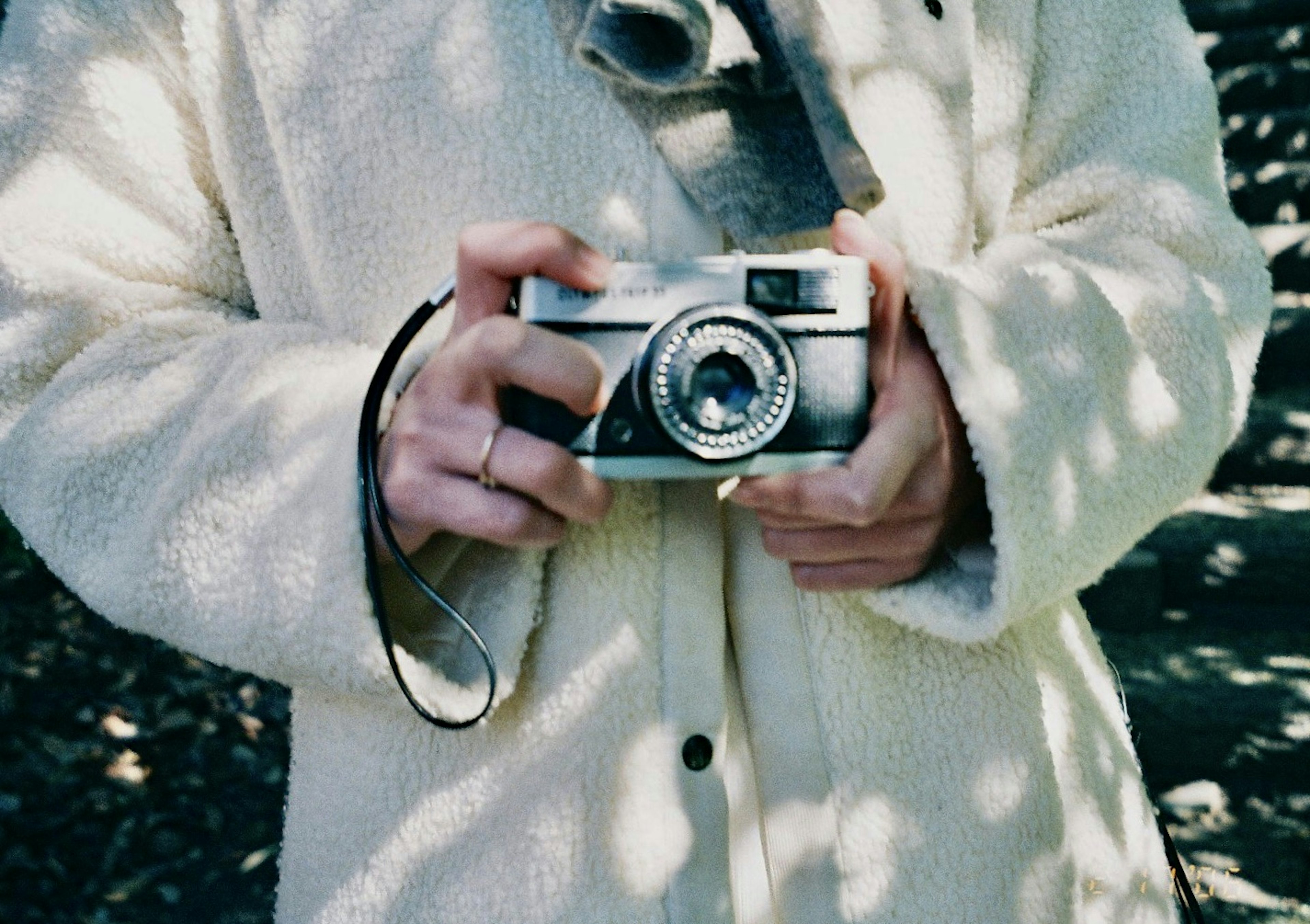 Person holding a film camera wearing a white coat