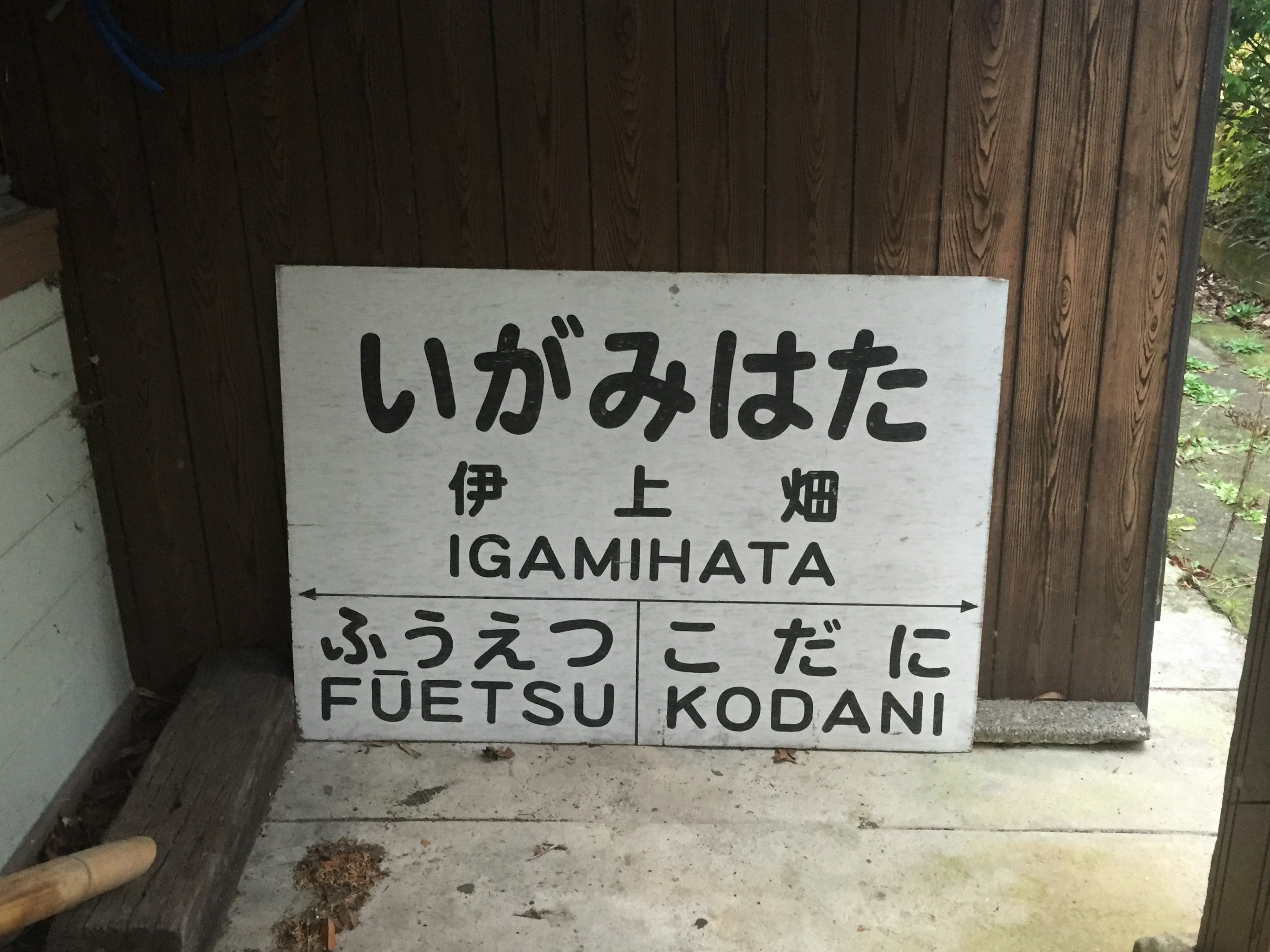 Tanda untuk Igamihata tertulis dalam bahasa Jepang dan Inggris di dinding kayu