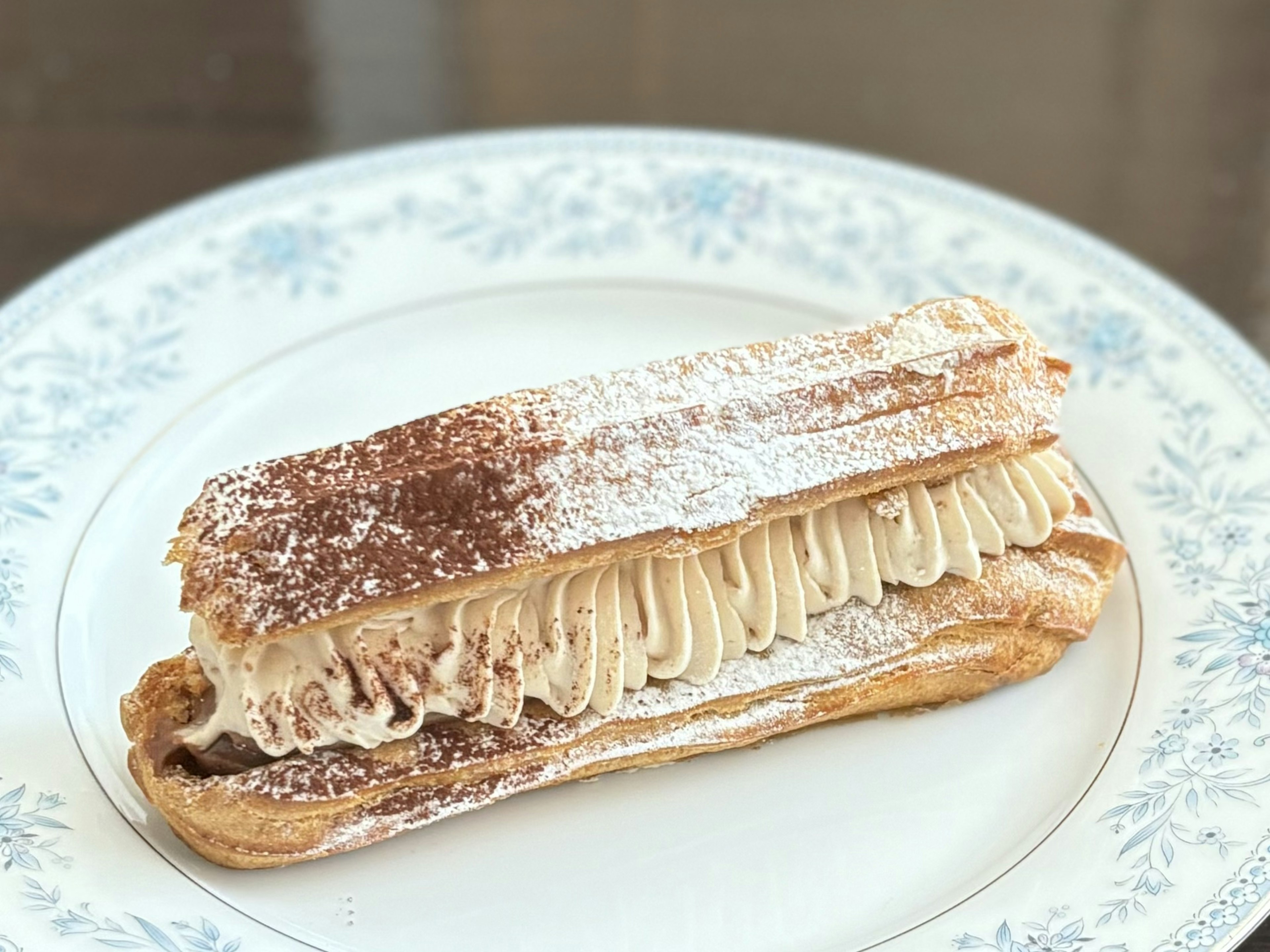 A cream-filled pastry on a decorative white plate