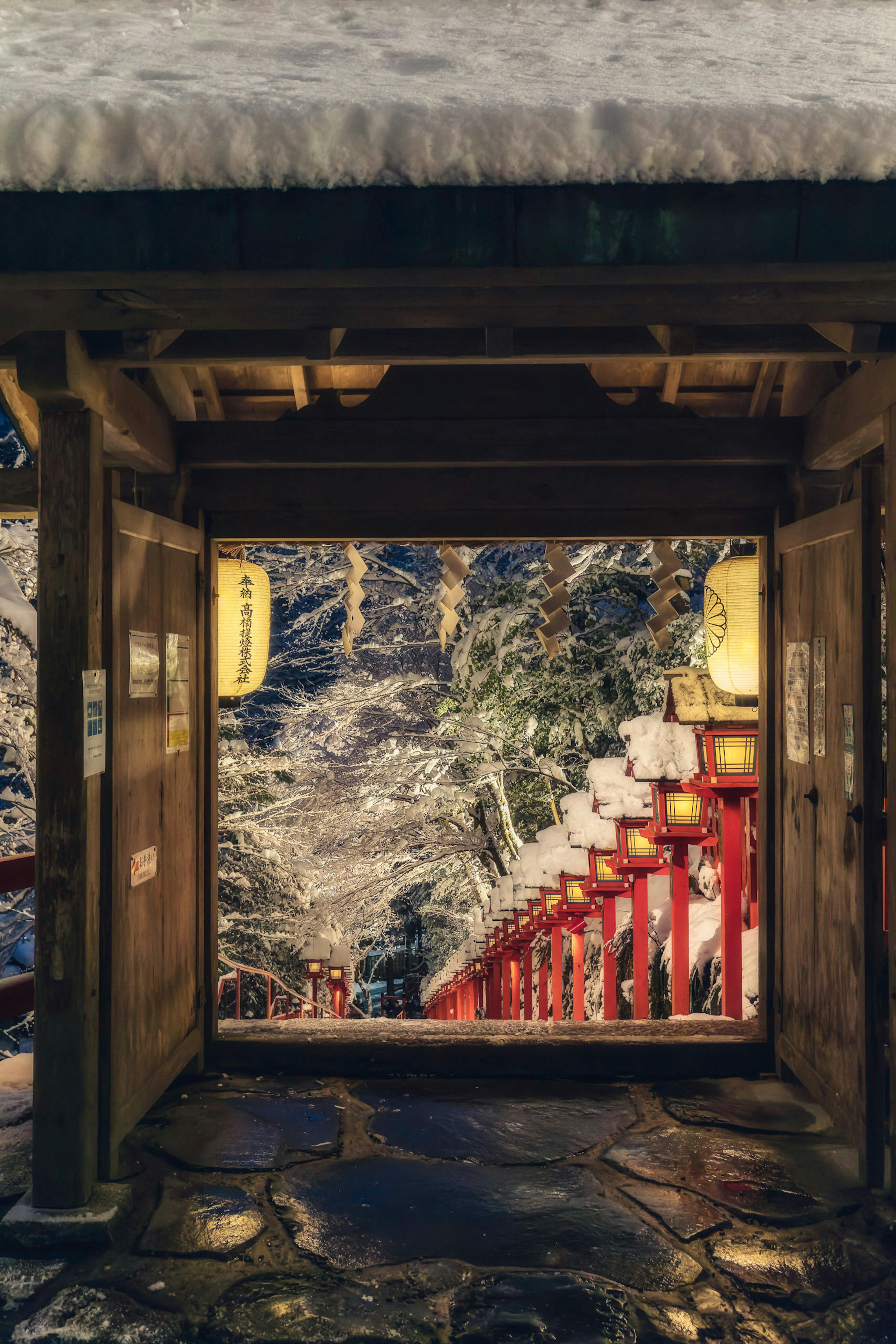 雪に覆われた赤い階段が見える神社の入り口