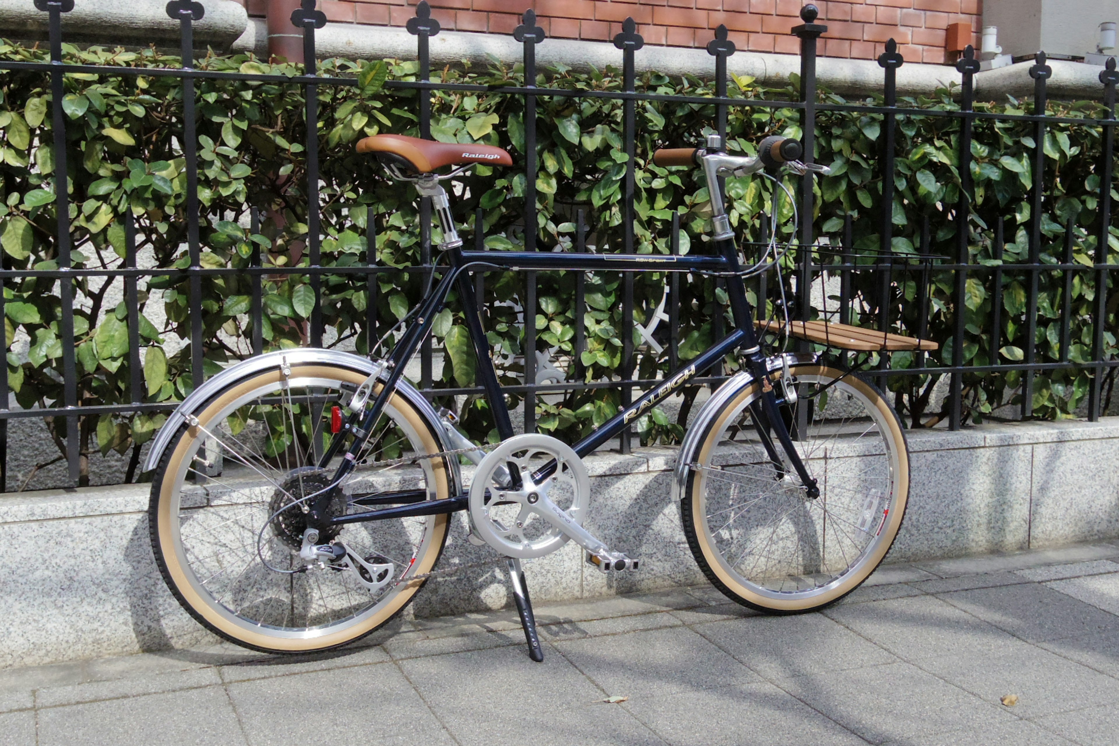 Un vélo pliant noir garé devant un feuillage vert