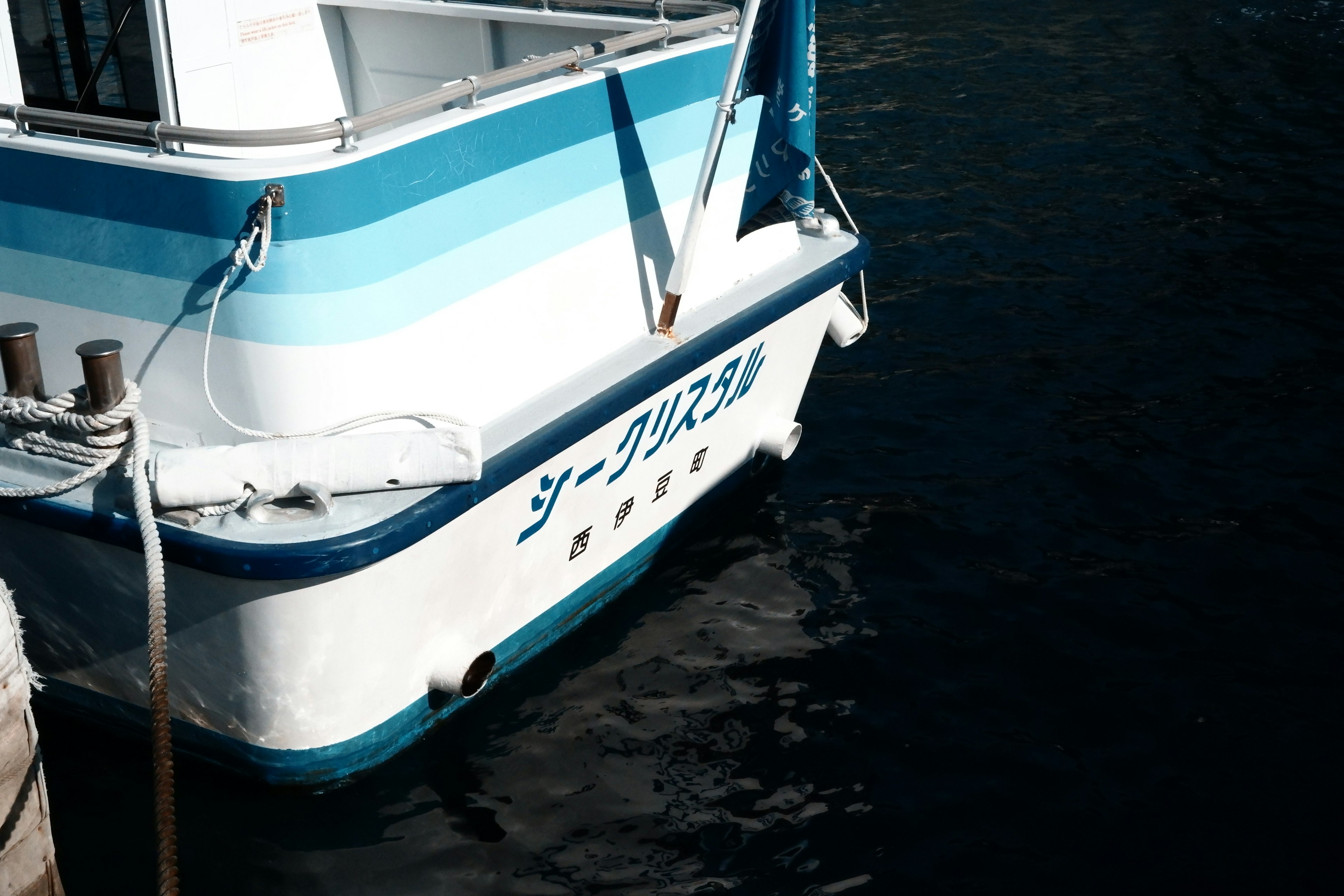 A blue striped boat's stern floating on the water