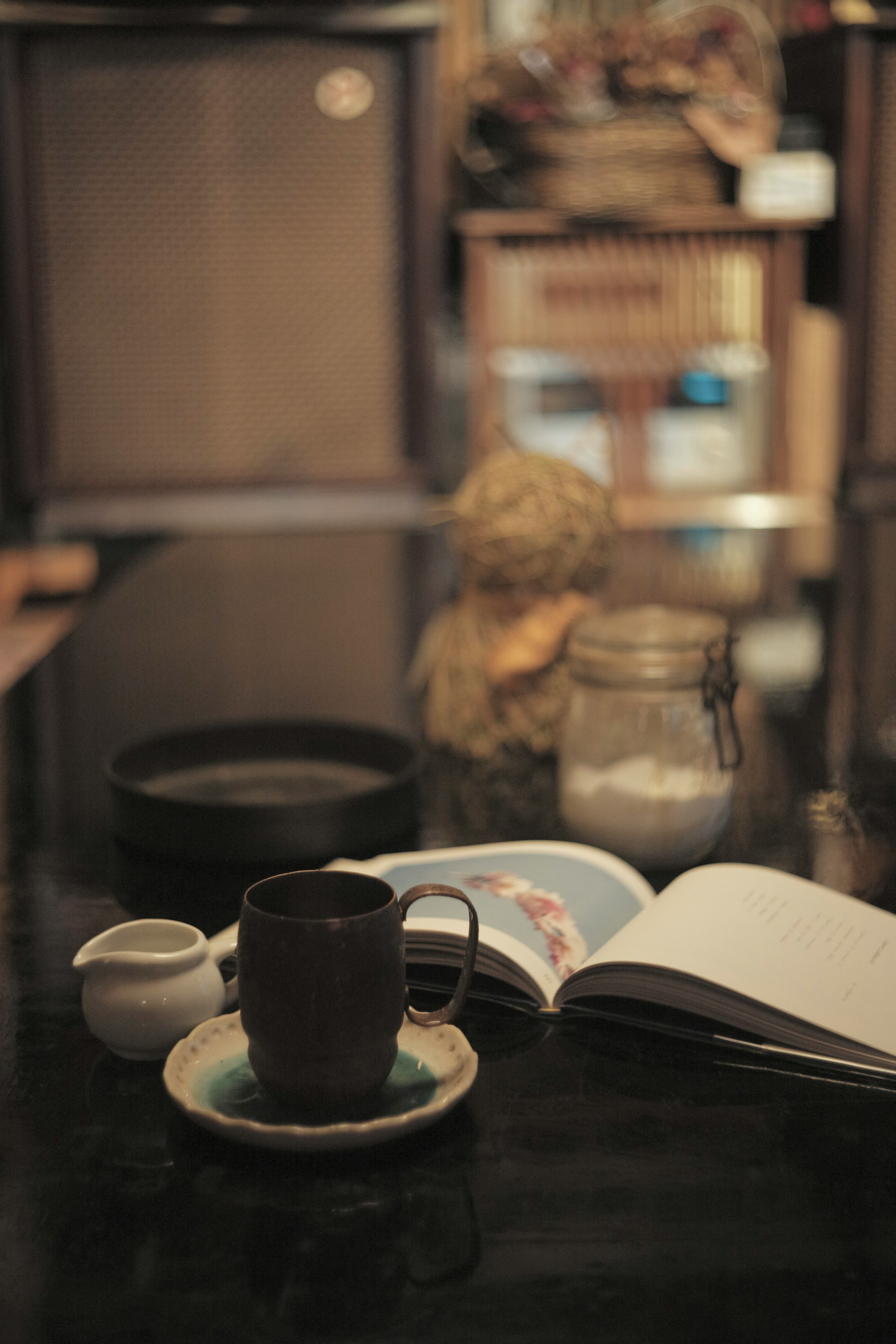 Kaffeetasse und ein offenes Buch auf einem Tisch mit einem Plüschtier im Hintergrund