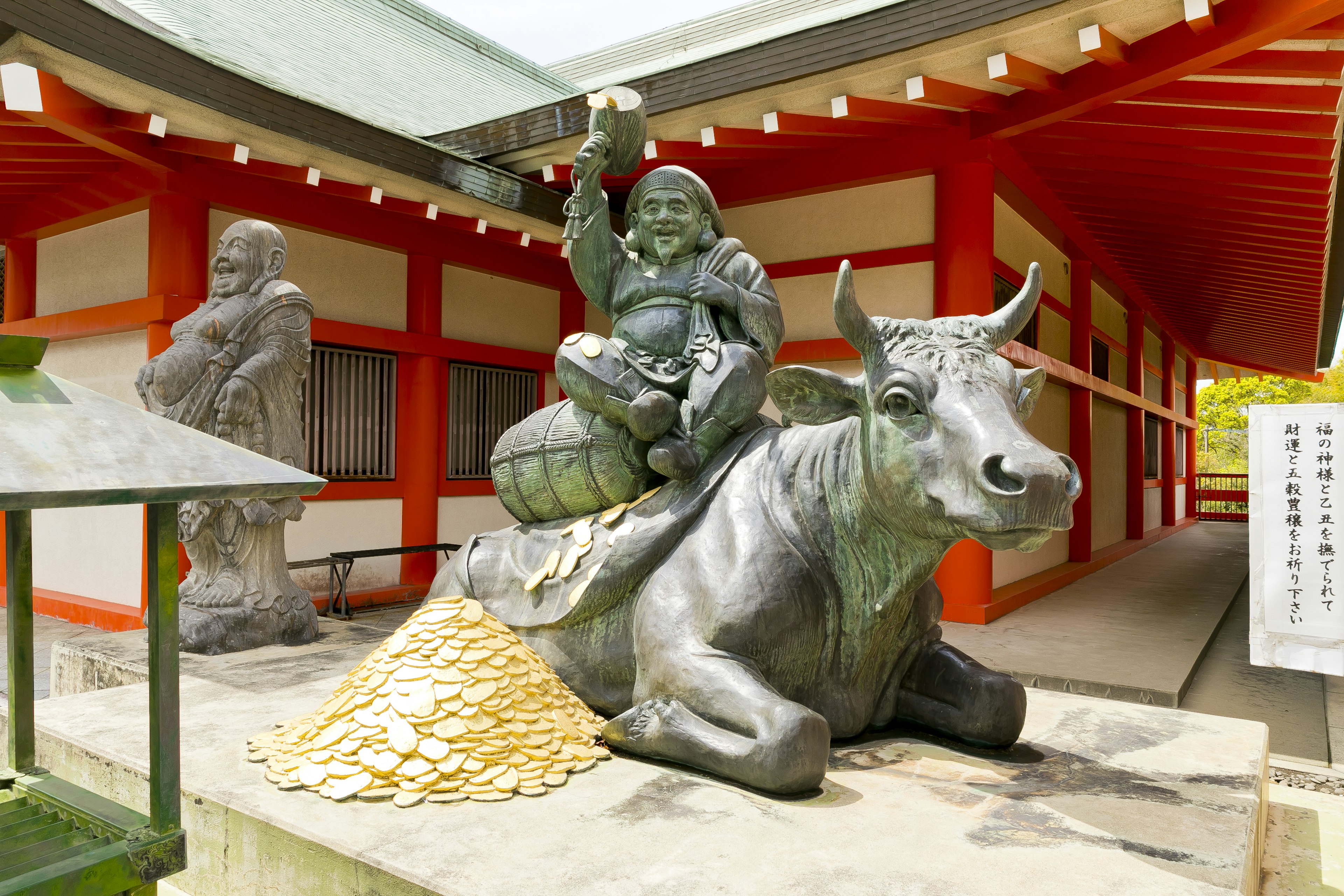 牛に乗る神の銅像と背景の赤い建物