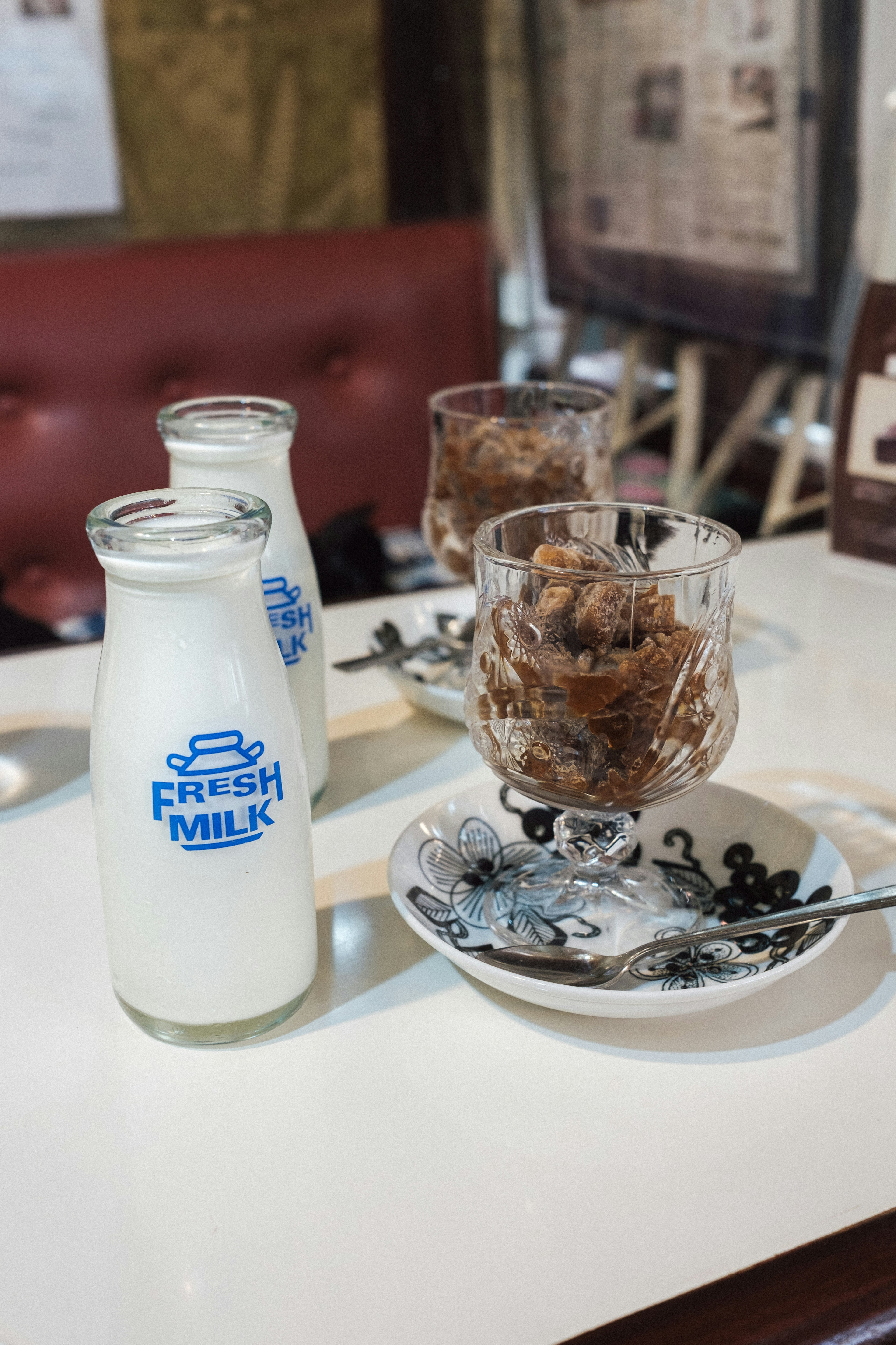 A cafe table featuring a bottle of fresh milk and chocolate dessert in a glass